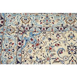 Central Persian Nain hand-knotted rug, ivory field with central medallion in tones of indigo and blue, issuing vinery, palmettes and floral sprays with conforming spandrels, dark blue main border of floral vinery and stylized palmettes, framed by multiple guard borders, with cotton fringe ends 
