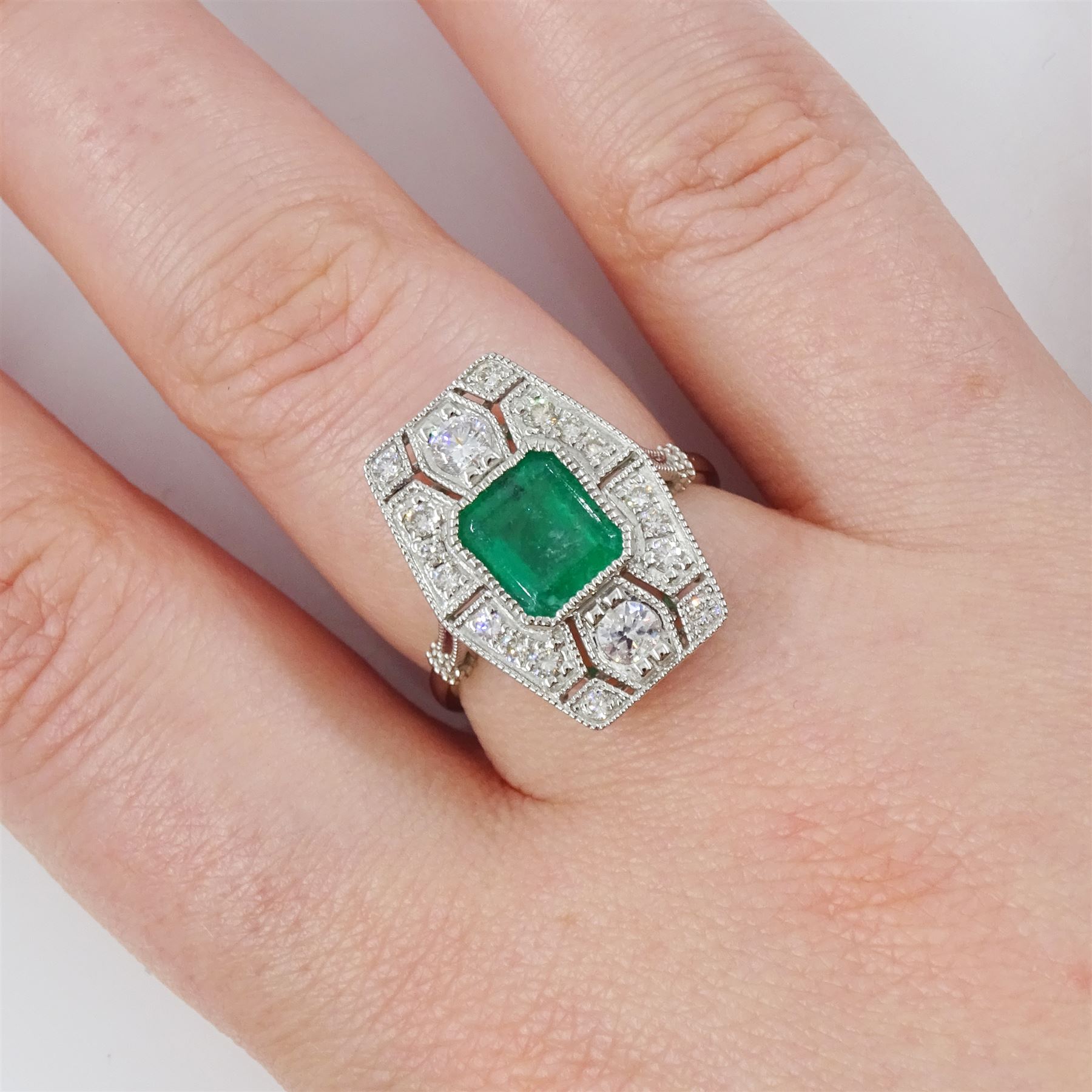 Platinum emerald and diamond dress ring, milgrain set with a single octagonal cut emerald of 1.26 carat, surrounded by round brilliant cut diamonds in an pierced design setting, stamped PT 950, total diamond weight 0.47 carat