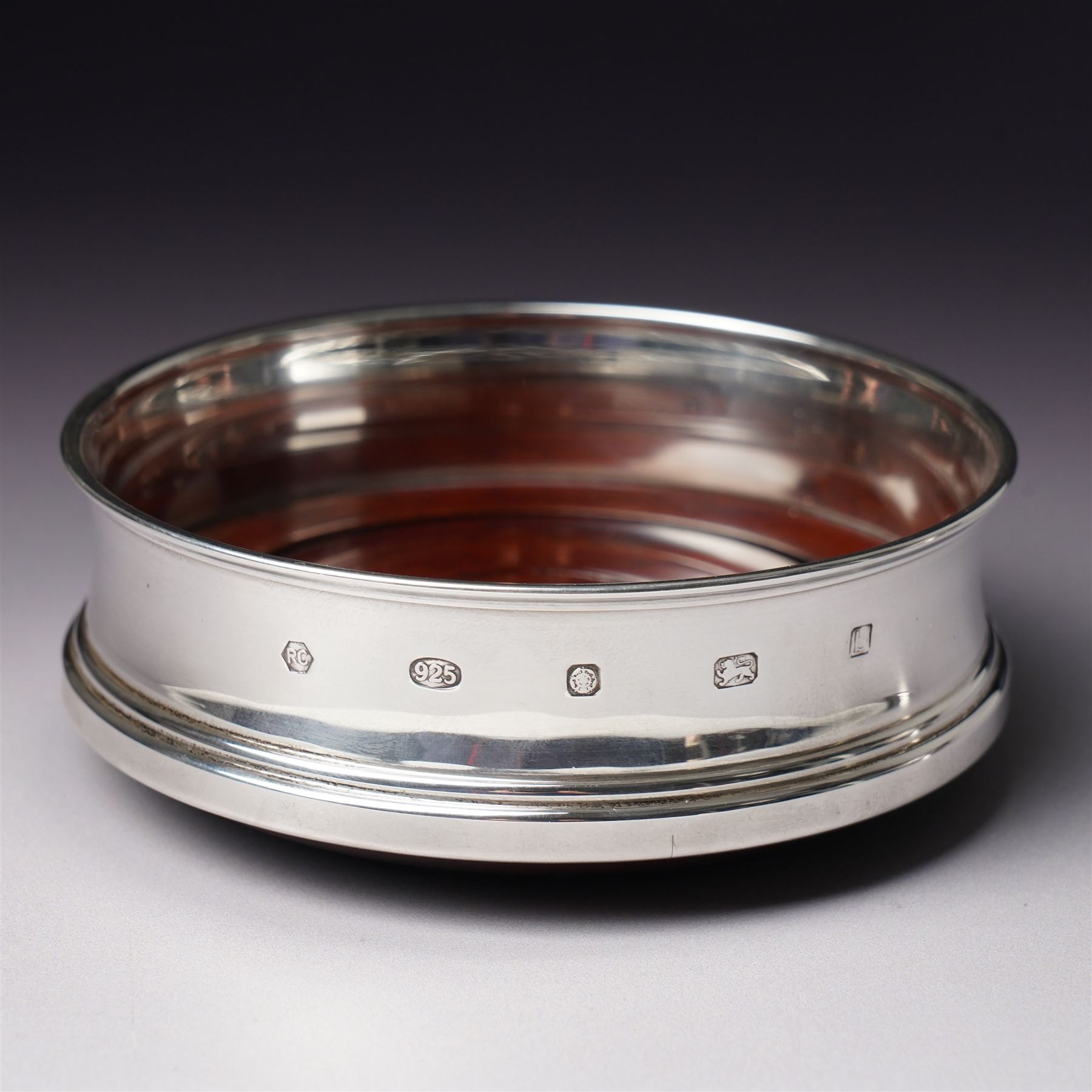 Edwardian silver bowl with embossed decoration on a short pedestal foot D11cm Birmingham 1904 Maker A & J Zimmerman Ltd and a modern silver coaster with turned wooden base D9.5cm Sheffield 2001 (2)