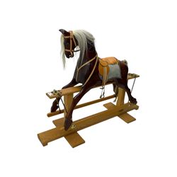 Contemporary carved wooden rocking horse, with leather saddle and bridle, horsehair mane and tail, raised on a pine stand with swing iron supports