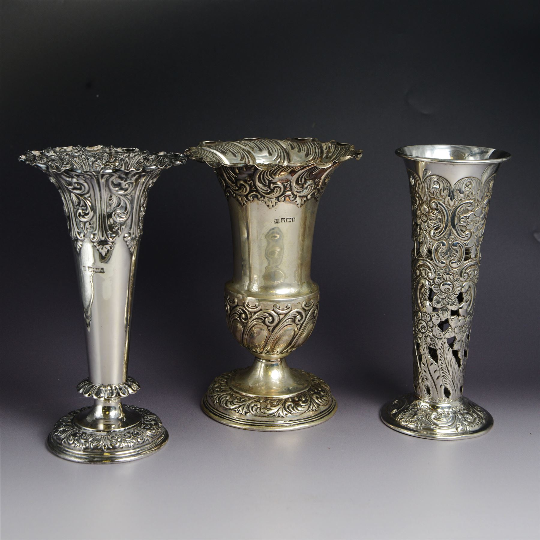 Three late 19th century/early 20th century silver vases, of trumpet form, all embossed with floral and foliate decoration, one example with weighted base, all hallmarked, tallest H18cm