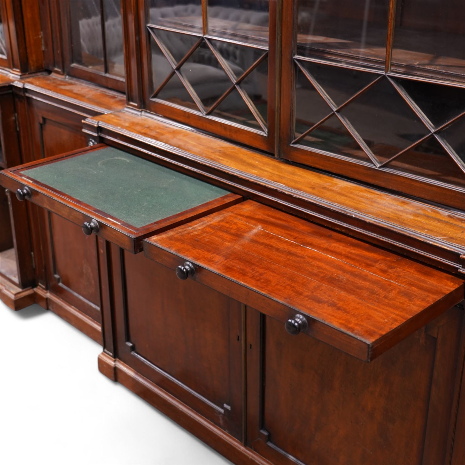 Large Georgian mahogany library bookcase, projecting moulded cornice with row of globular mounts, adjustable shelving enclosed by six astragal glazed doors, fitted with two slides and six panelled cupboard doors, two banks of five drawers, on moulded plinth base; together with two pairs of associated astragal glazed doors in mahogany, from the same property (W55.5cm x H168cm & W48cm x 168cm)