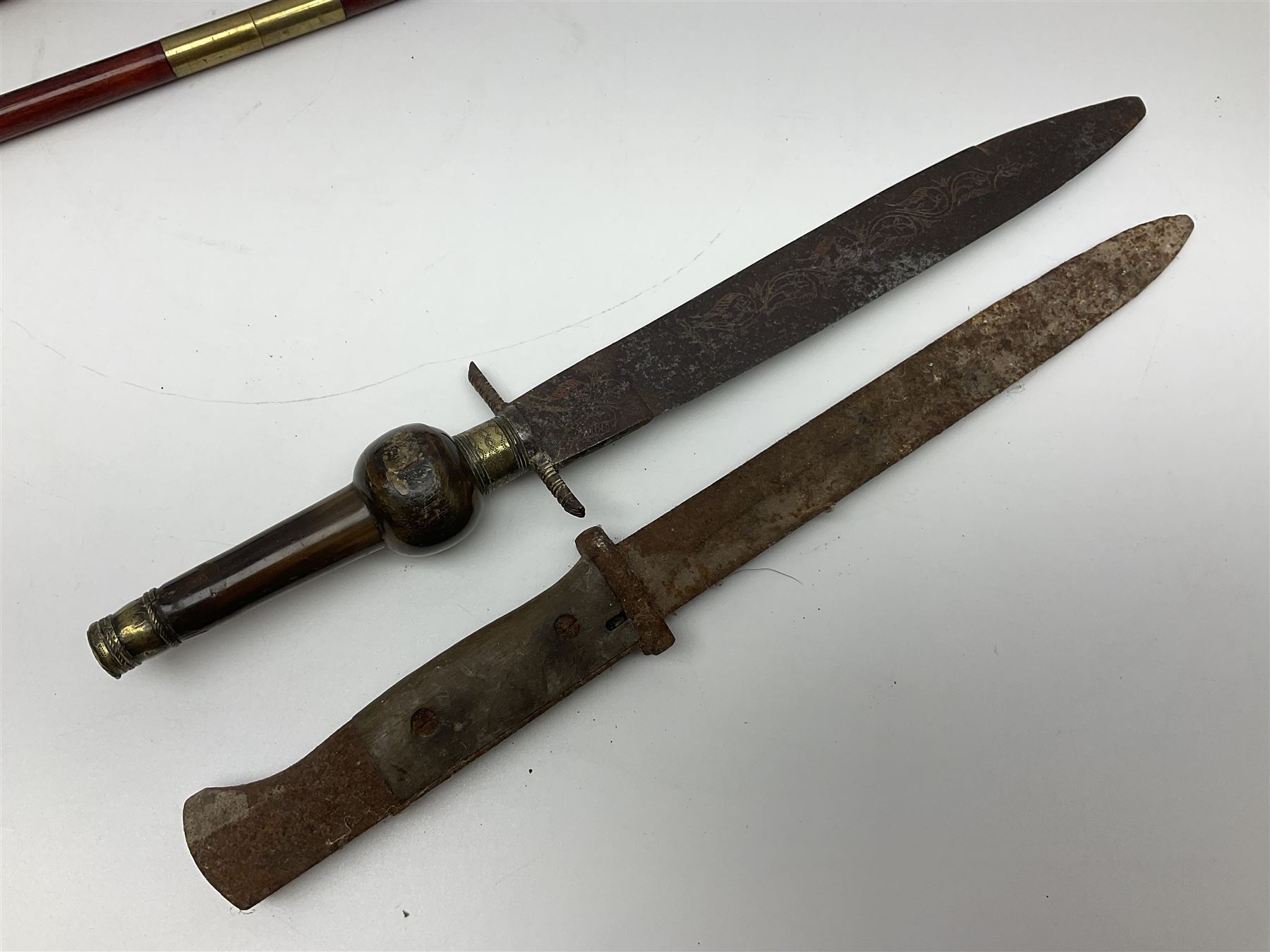 19th century continental folding knife with 15.5cm single edged blade, the pierced brass and iron handle with remains of horn grips L21.5cm overall closed; turned horn handled knife with foliate engraved blade; battlefield relic German 1884/98 knife bayonet; iron spear head; leather covered swagger stick; and two-piece gun cleaning rod