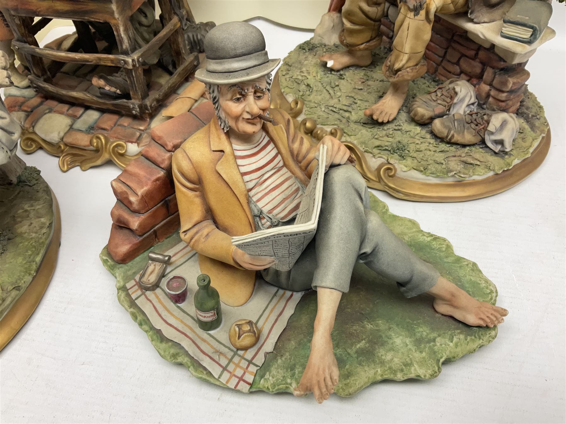 Four Capodimonte figure groups, to include tramp figures, shoemaker figure etc