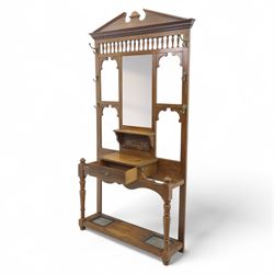Edwardian walnut hall stand, the shaped pediment above turned spindle gallery and bevelled mirror, fitted with brass double coat hooks, single drawer with cast handle and carved frieze, flanked by turned supports, lower platform fitted with twin metal drip trays