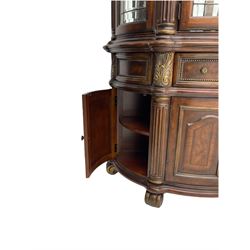  Kevin Charles American walnut demi lune display cabinet with illuminated interior, projecting cornice, two bevel edge glazed doors enclosing two adjustable shelves above single drawer and four cupboard doors with wine rack, carved scrolling supports
