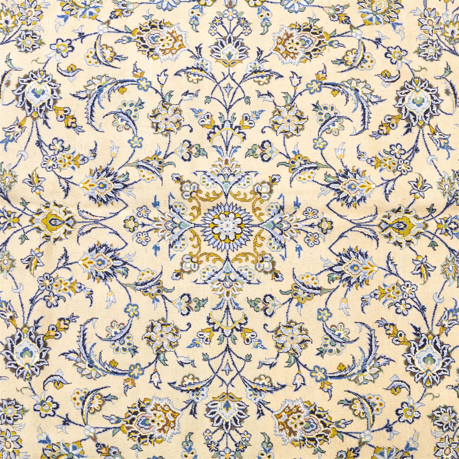 Central Persian Kashan hand-knotted carpet, pale ivory ground, decorated with an all-over scrolling floral design of palmettes rosettes, and leafy vine work enclosed by a wide floral border and multiple guard borders in tones of soft blues, sage green, muted gold, and ivory, with cotton fringe ends
