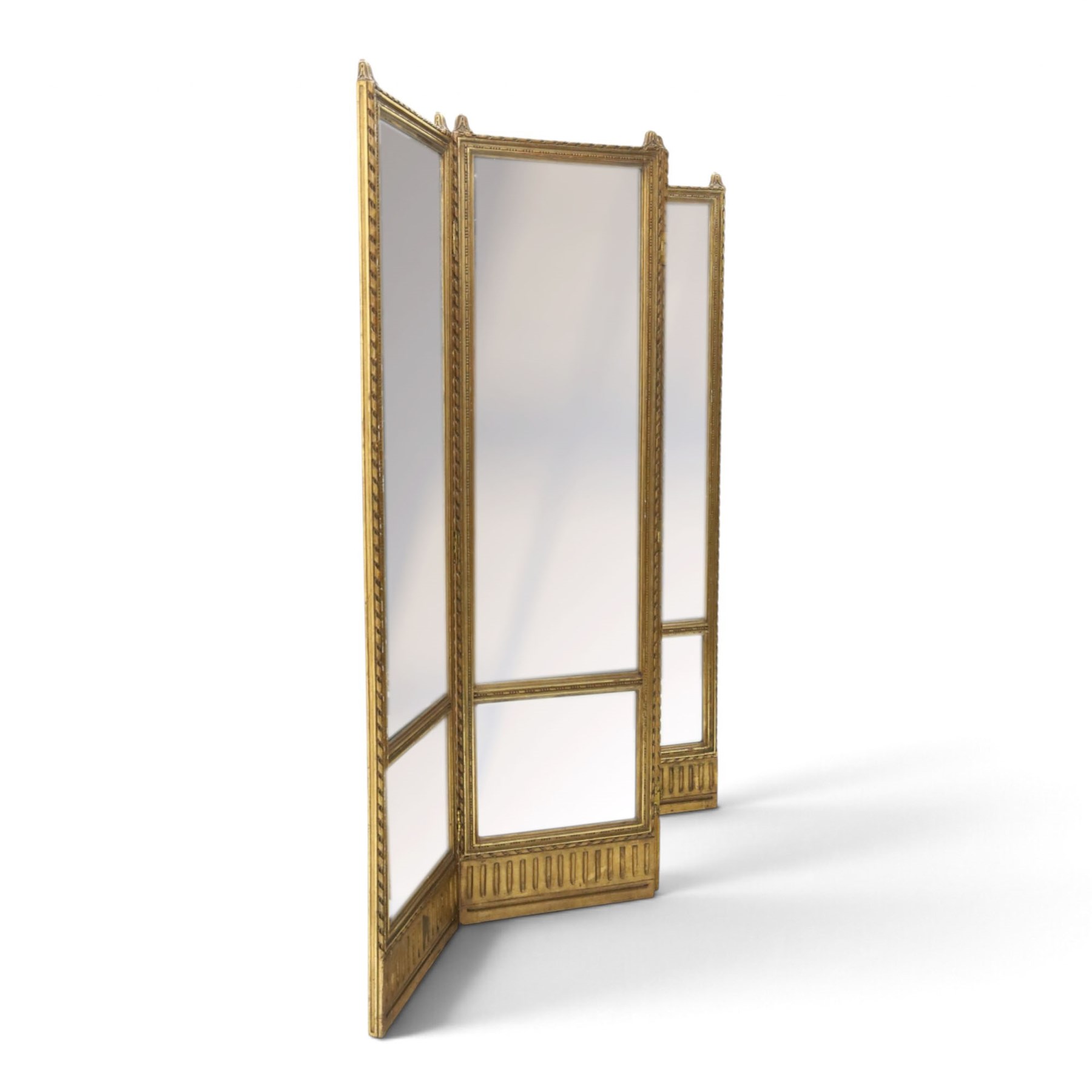 Early 20th century gilt and bevelled mirrored four panel folding screen, with two mirrors per side, flanked by beaded edges and scrolled finials, arcaded carved frieze