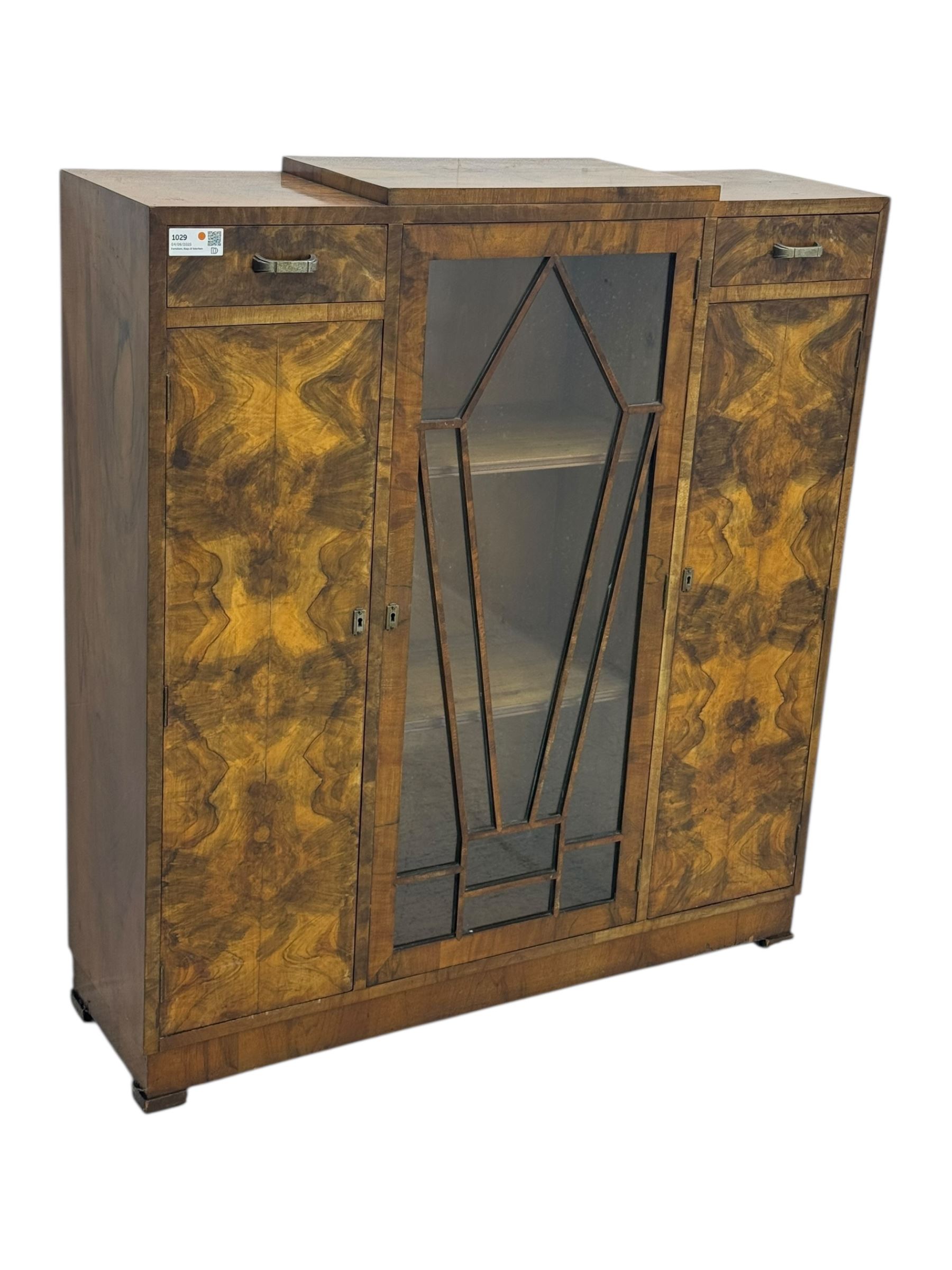 Art Deco burr walnut drinks cabinet, geometric central glazed astragal door enclosing two fixed shelves, flanked by symmetrical bookmatched veneered cupboards with drawers above 