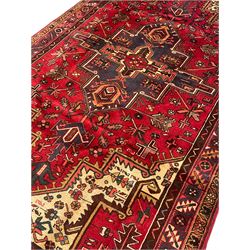 Persian Heriz, red ground and decorated with stylised flower and plant motifs, triple band border 