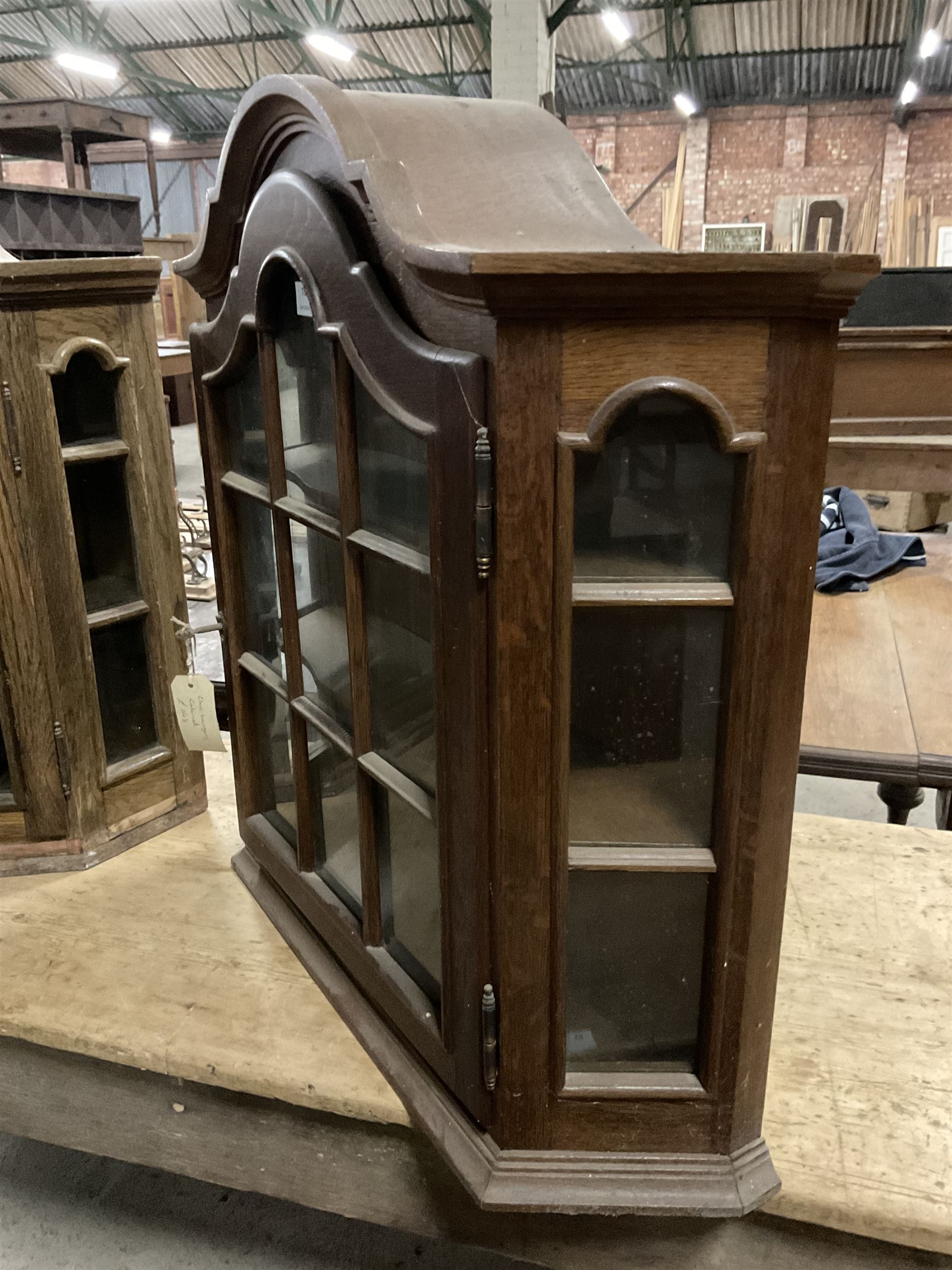 Dutch design oak wall hanging apothecary cabinet, of arched form with single astragal style glazed door enclosing single shelf (W69cm D18cm H69cm); together with another similar of corner form (W75cm D48cm H69cm) - THIS LOT IS TO BE COLLECTED BY APPOINTMENT FROM THE OLD BUFFER DEPOT, MELBOURNE PLACE, SOWERBY, THIRSK, YO7 1QY