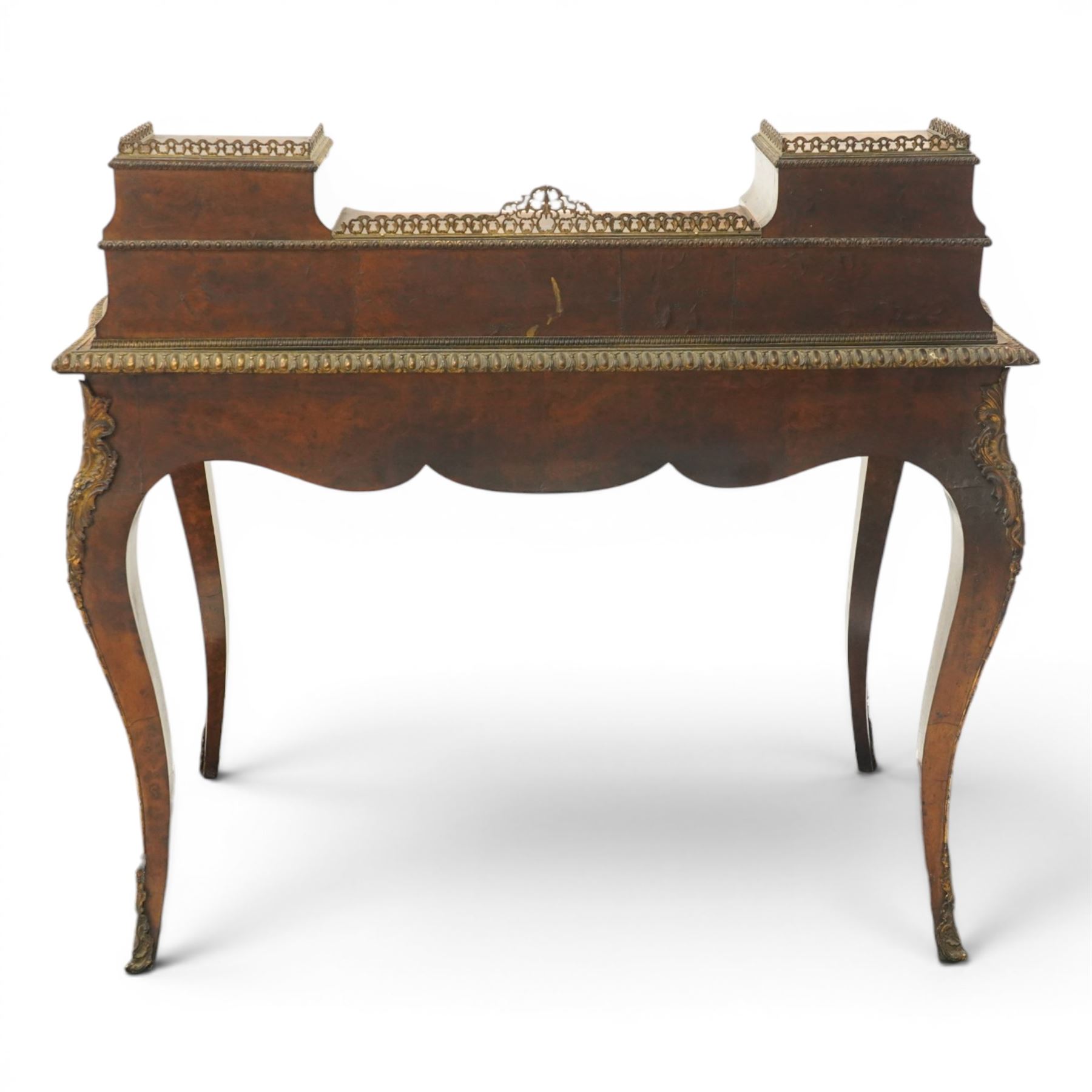 Victorian figured walnut and kingwood-banded ladies writing table, the raised superstructure with three-quarter pierced brass raised gallery back, fitted with five assorted drawers, the serpentine shaped top with oval inset leather surface, the bronze edge of egg and dart form with cartouche corners, fitted with central frieze drawer with inset Sevres-style floral ceramic plaque, raised on cabriole supports with gilt metal mounts