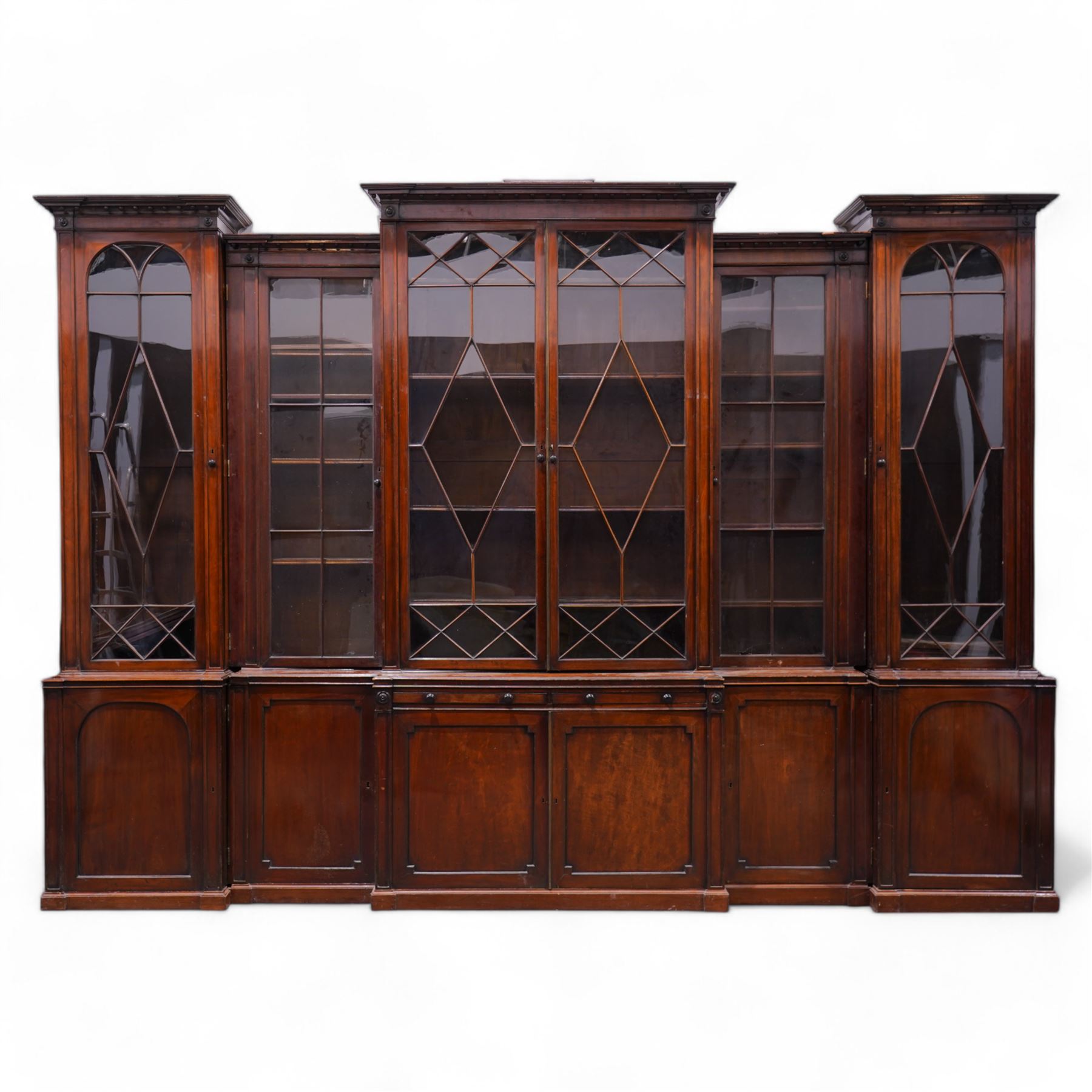 Large Georgian mahogany library bookcase, projecting moulded cornice with row of globular mounts, adjustable shelving enclosed by six astragal glazed doors, fitted with two slides and six panelled cupboard doors, two banks of five drawers, on moulded plinth base; together with two pairs of associated astragal glazed doors in mahogany, from the same property (W55.5cm x H168cm & W48cm x 168cm)