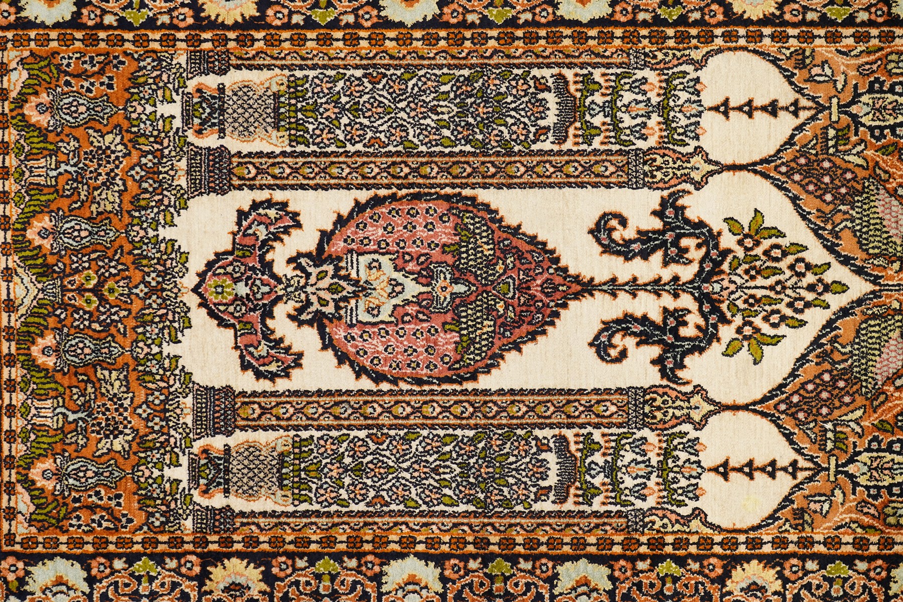 Indian silk-inlaid prayer rug, ivory field decorated with a triple-arched Mirab motif, pendant medallion, paired birds and flowering vases, enclosed by a black ground guard band of scrolling foliage and palmettes