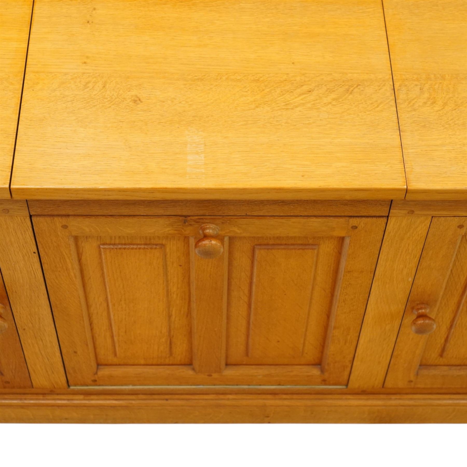 Seahorseman by Shaw & Riley - bespoke large Yorkshire oak corner sideboard or media unit, of L-shape form, with three cupboard doors, a fall front drawer over a regular drawer, a lift up panel for a record player, multiple apertures for wires, raised on a plinth base, with signature Seahorse carving from the workshop of A. Shaw & Riley Ltd, Hessay