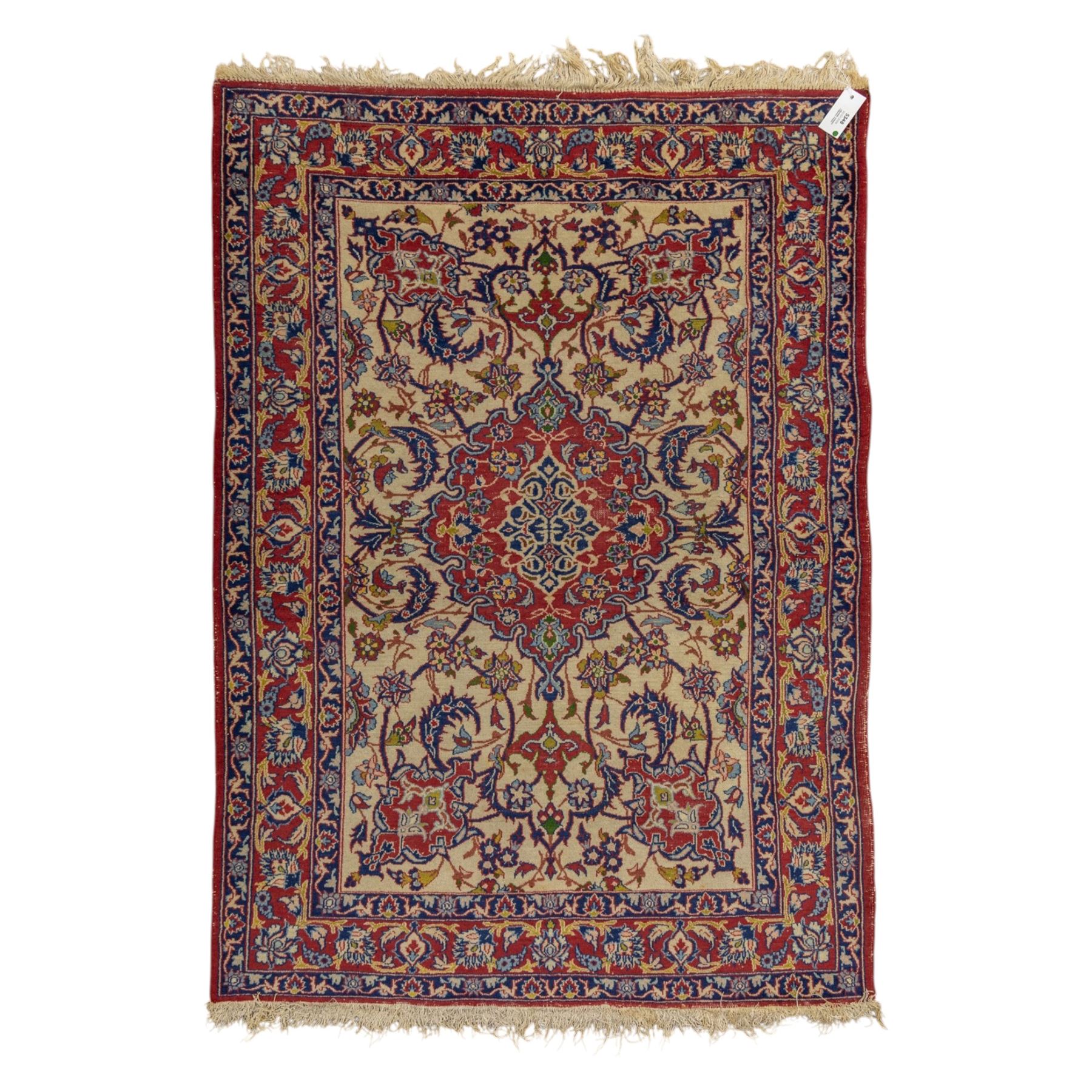Kashan design wool rug, with red floral medallion on a cream field, decorated with scrolling foliate motifs in blue, red and green tones, enclosed by red and blue floral borders with fringed ends