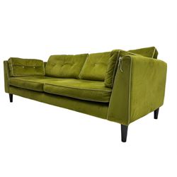 Mid-century design four seat sofa, upholstered in peridot green fabric with contrasting piping and buttons, on ebonised tapering feet