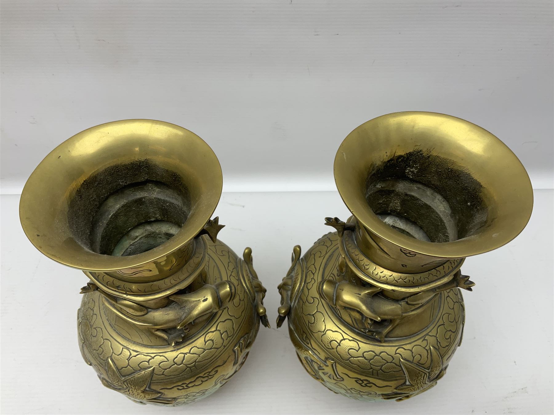 Pair of Chinese brass vases, of ovoid form with elongated neck and fluted rim, decorated in high relief with a dragon chasing a flaming pearl around the neck, the body with dragons, birds and buildings, with character marks beneath, H25cm