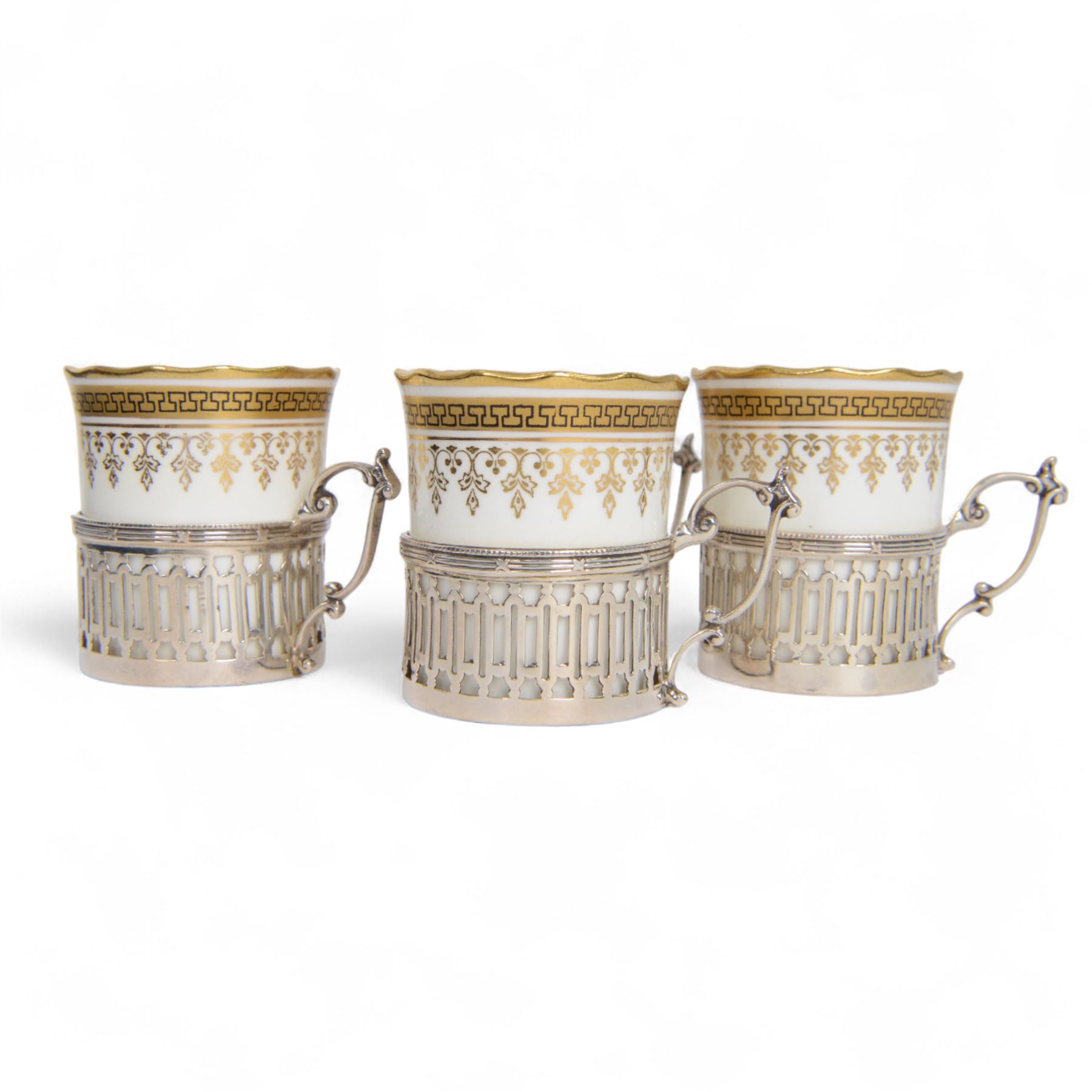 Boxed set of six Aynsley coffee cans and saucers, decorated with gilt greek key border, the cans within silver mounts, hallmarked Birmingham 1911