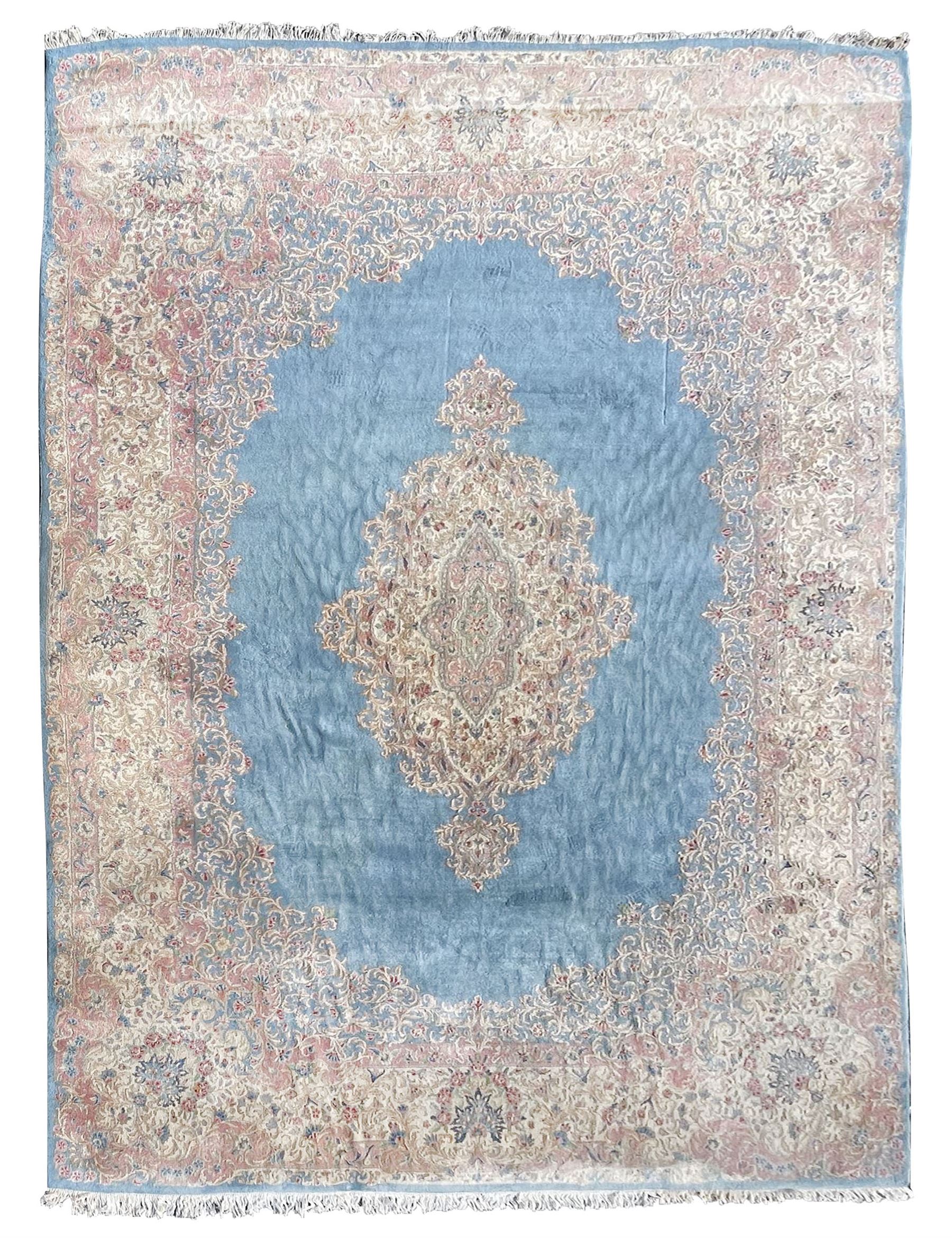 Large Persian design carpet, plain light blue field with floral design central medallion, scrolling foliate spandrels and borders decorated with flower heads