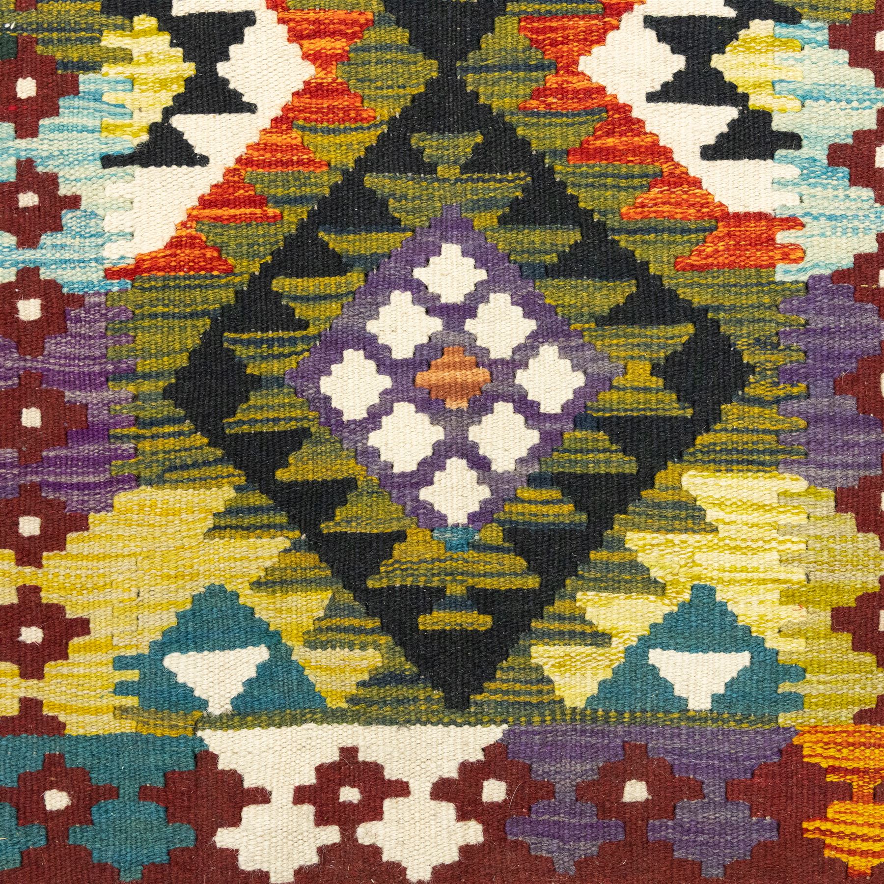 Chobi flatweave kilim runner, repeating diamond medallion design in a vibrant palette of green, red, and teal, ivory and black, within a narrow floral border