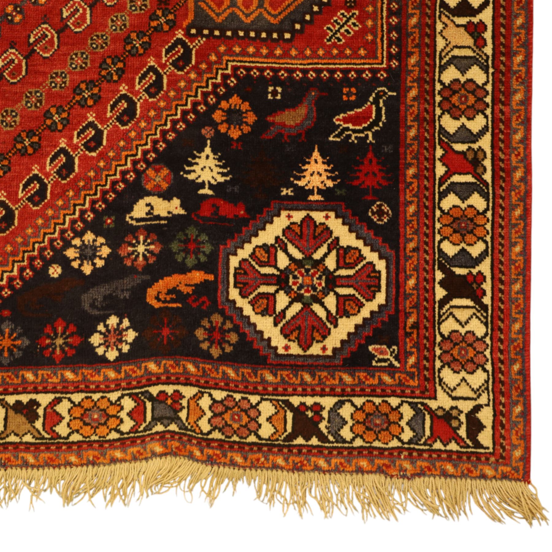 Persian Shiraz rug, hand-knotted tribal rug, bold geometric central medallion, set within a large hexagonal crimson field with angular stepped corners in dark blue, with boteh motifs, rosettes, and other tribal symbols arranged in diagonal rows, the corners with indigo spandrels decorated with zoomorphic and arboreal motifs, main border composed of a floral meander motif with large rosette, flanked guard borders with vine and leaf motifs 