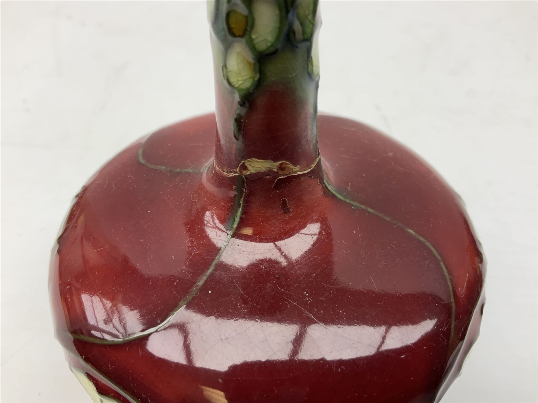 Three Minton Secessionist vases, with tube-lined stylised flower decoration, two upon a red ground and third upon a purple ground, all with printed mark to base 'Minton Ltd, No. 33', H13cm