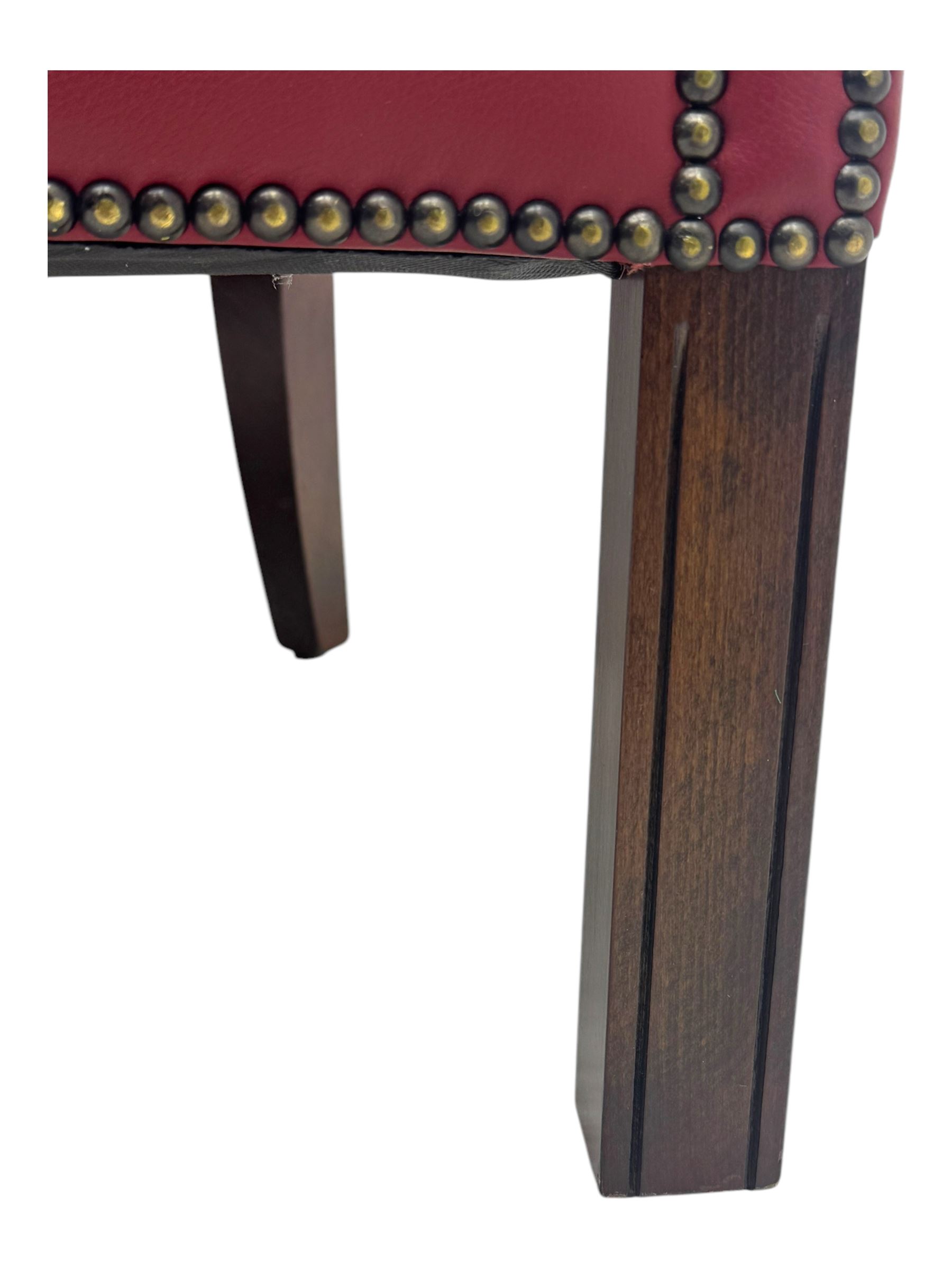 Kingsgate - contemporary 'Devon' bucket armchair, upholstered in red leather with buttoned backrest, rolled arms and brass stud detailing, raised on four dark wood supports with vertical carving