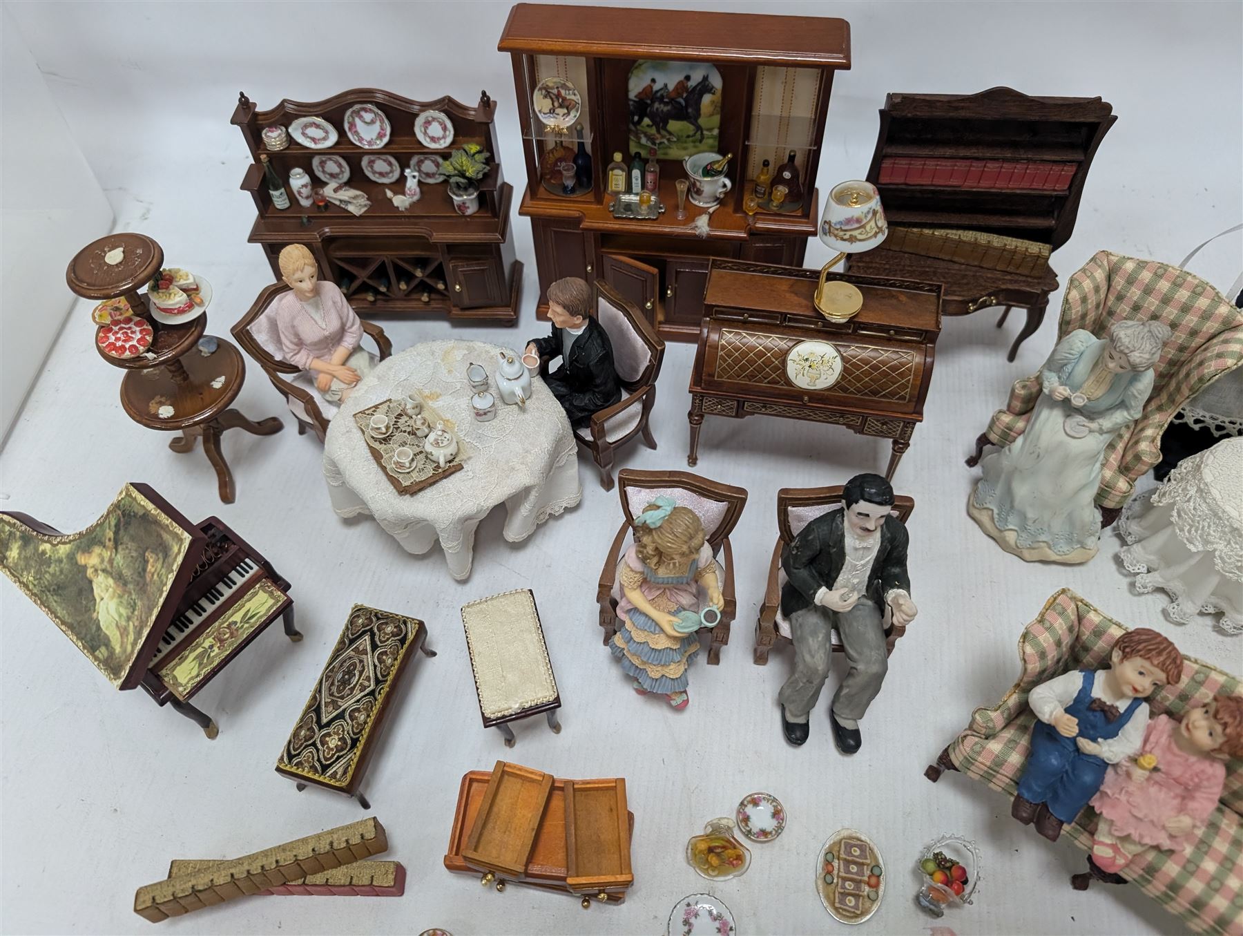 Dolls house drawing room furniture, including dressers, pink and green checked sofa and armchairs, bureau, chairs, piano, eight figures and a collection of afternoon tea miniatures