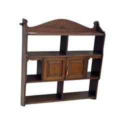 20th century carved mahogany hanging wall shelf, shaped top rail with carved fan motif over central twin cupboard flanked by fixed shelves, open base with three-tier shelving