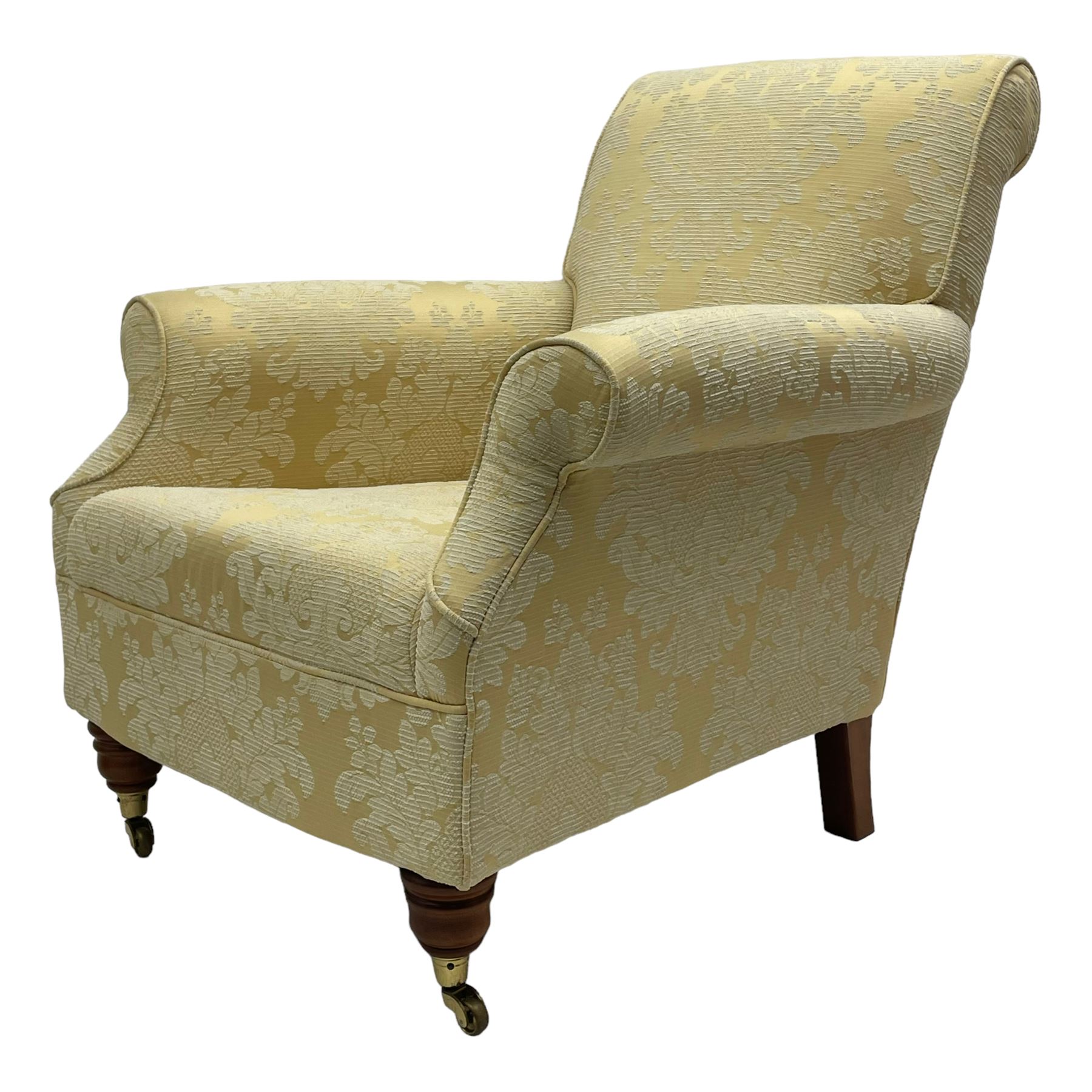Traditionally shaped hardwood-framed armchair, rolled back and arms, upholstered in pale gold and cream damask fabric with repeating foliate pattern, on turned feet with brass cups and castors