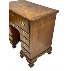 Early 18th century Queen Anne figured walnut kneehole desk with secretaire drawer, moulded and book matched top with walnut band, the top drawer with fall front enclosing small drawers and pigeon holes, fitted with nine drawers and central recessed cupboard, on ogee bracket feet