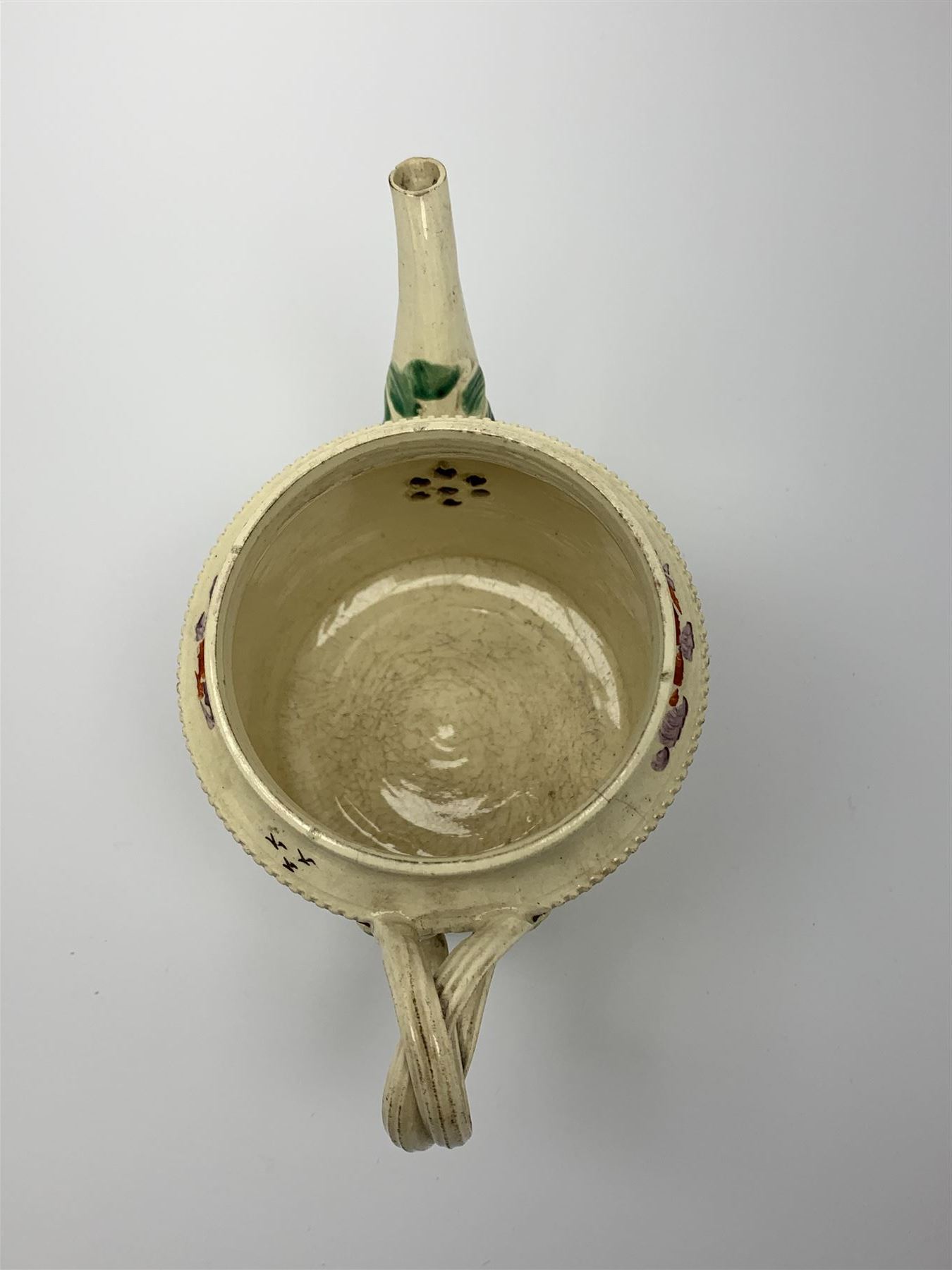 18th century creamware teapot, probably Leeds, with reeded entwined handle and floral finial to the cover, the body with hand painted polychrome decoration of figure to one side, and floral spray to the other, collectors paper label beneath inscribed Leeds Pottery, H11.5cm