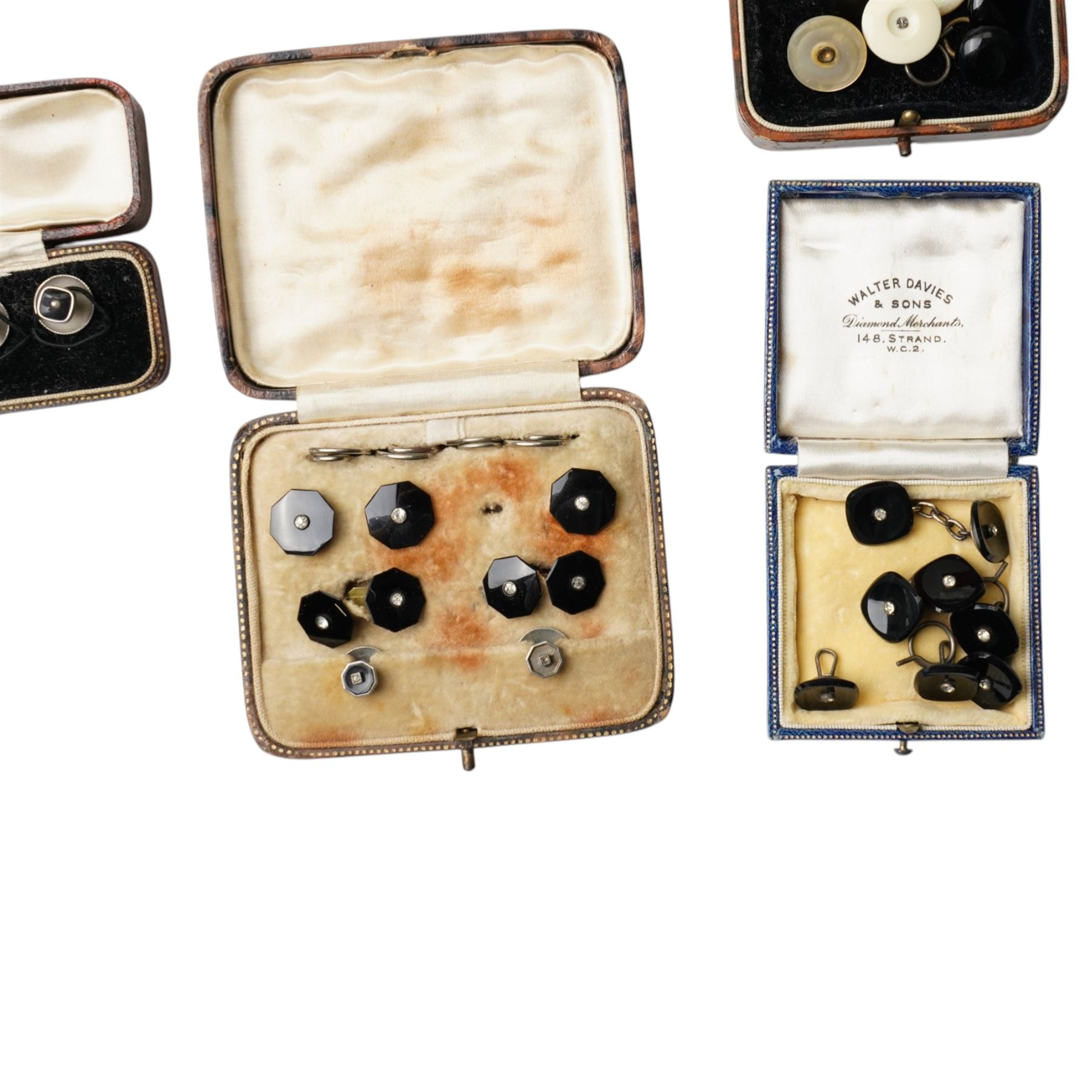 Early 20th century dress sets including onyx and paste examples, some stamped 935, paste set buckles and buttons, faux turquoise jabot pin, in the style of Bernard Instone, silver cufflinks etc, housed in an early 20th century red leather jewellery box