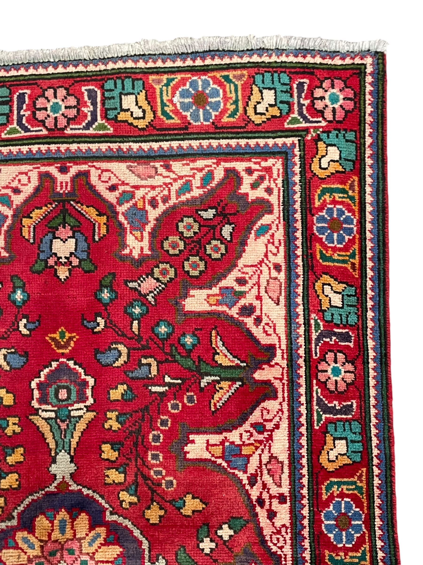 Persian Azerbaijan crimson ground rug, the field decorated with central floral motif and surrounded by trailing floral branches, enclosed within a shaped outer band with further floral decoration, the border with repeating flower heads, geometric guard stripes 