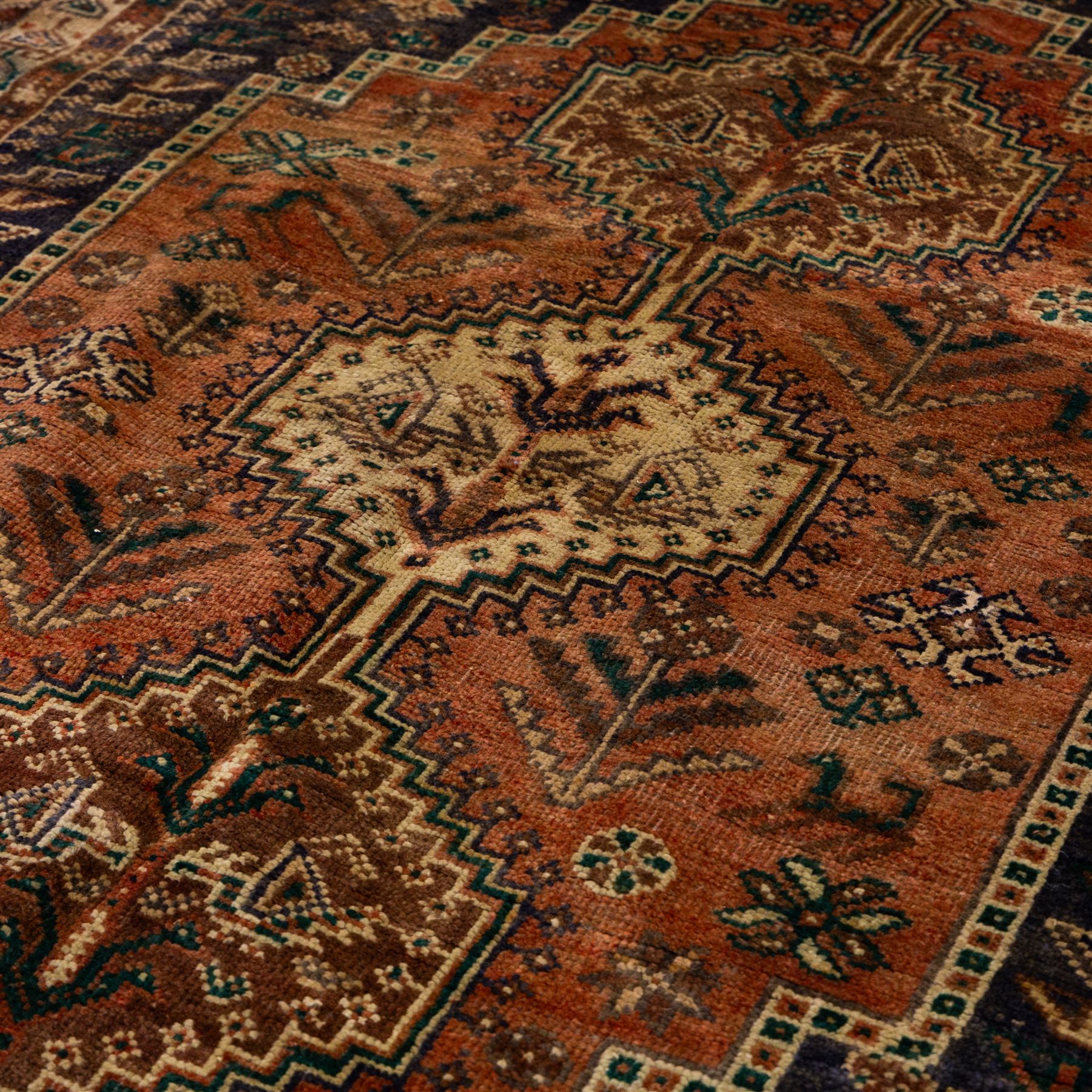 South West Persian Qashqai hand-knotted rug, salmon pink field with central stepped geometric medallion with issuing stylized tree and floral motifs, surrounded by angular devices, with indigo spandrels and multiple geometric borders, fringe ends 