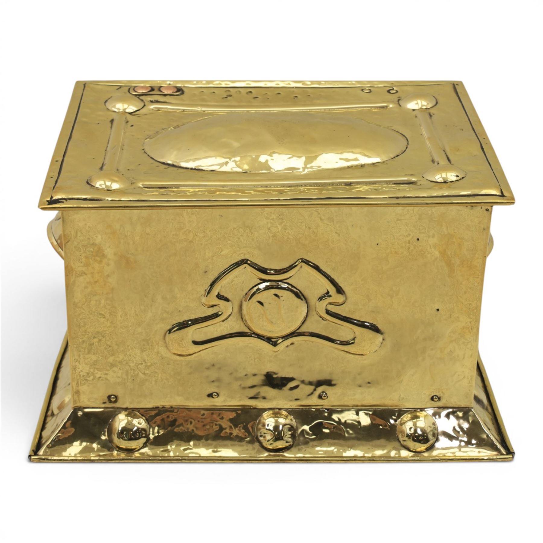 Art Nouveau brass coal box, the hinged rectangular cover embossed with a foliate design, hammered panelled sides with shaped carrying handles, on projecting plinth base with applied roundels