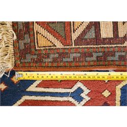 Caucasian Kazak indigo and vermillion ground rug, the geometric field boldly woven with two medallions interspersed with symbolic tribal motifs and shapes, with contrasting ivory guard band