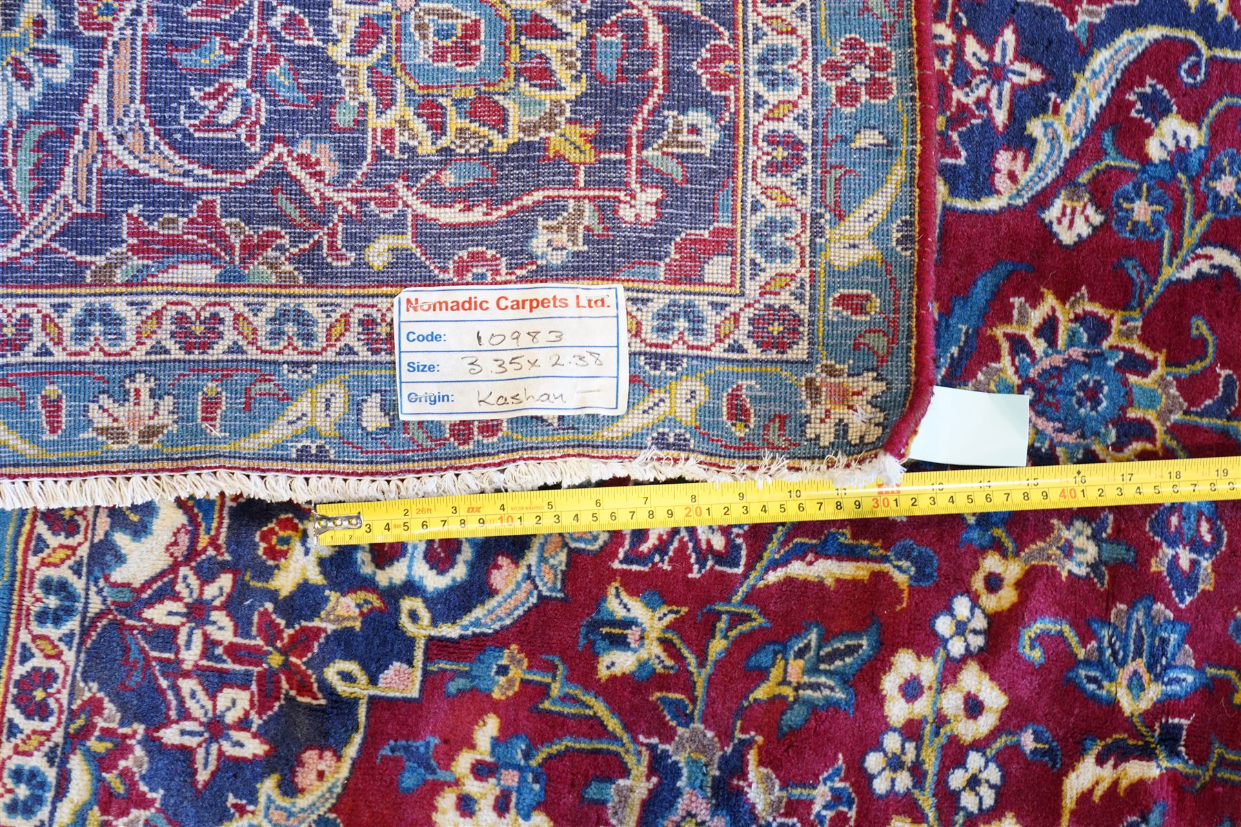 Central Persian Kashan hand-knotted carpet, crimson field with a central elaborate cusped medallion surrounded by elegant scrolling floral vine design incorporating stylized palmettes, rosettes and foliate sprays and similarly decorated spandrels enclosed by a dark indigo main border of floral arabesques between multiple guard stripes, cotton fringe ends 