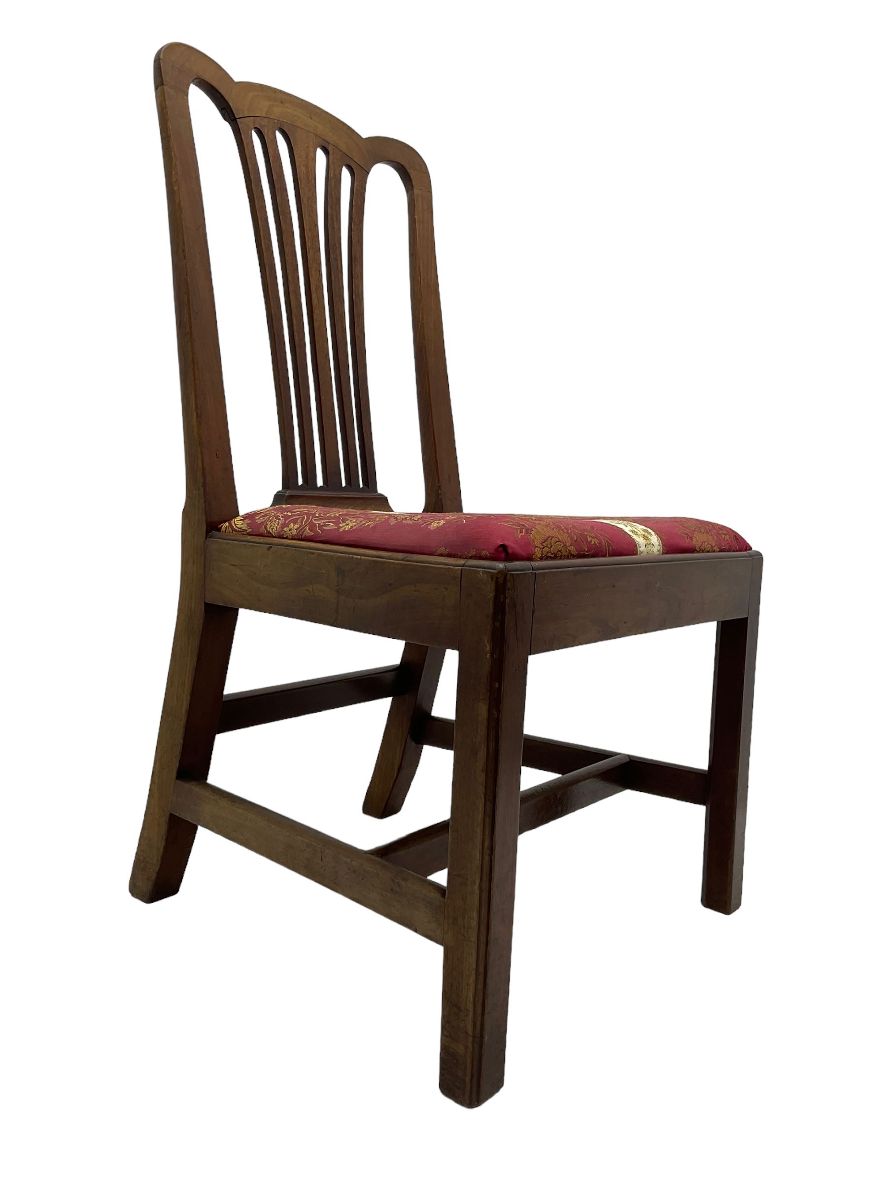 Set of six (5+1) George III mahogany dining chairs, shaped cresting rail over pierced and flared splat, drop-in seat upholstered in crimson and ivory floral patterned fabric, raised on chamfered square supports united by H-stretcher