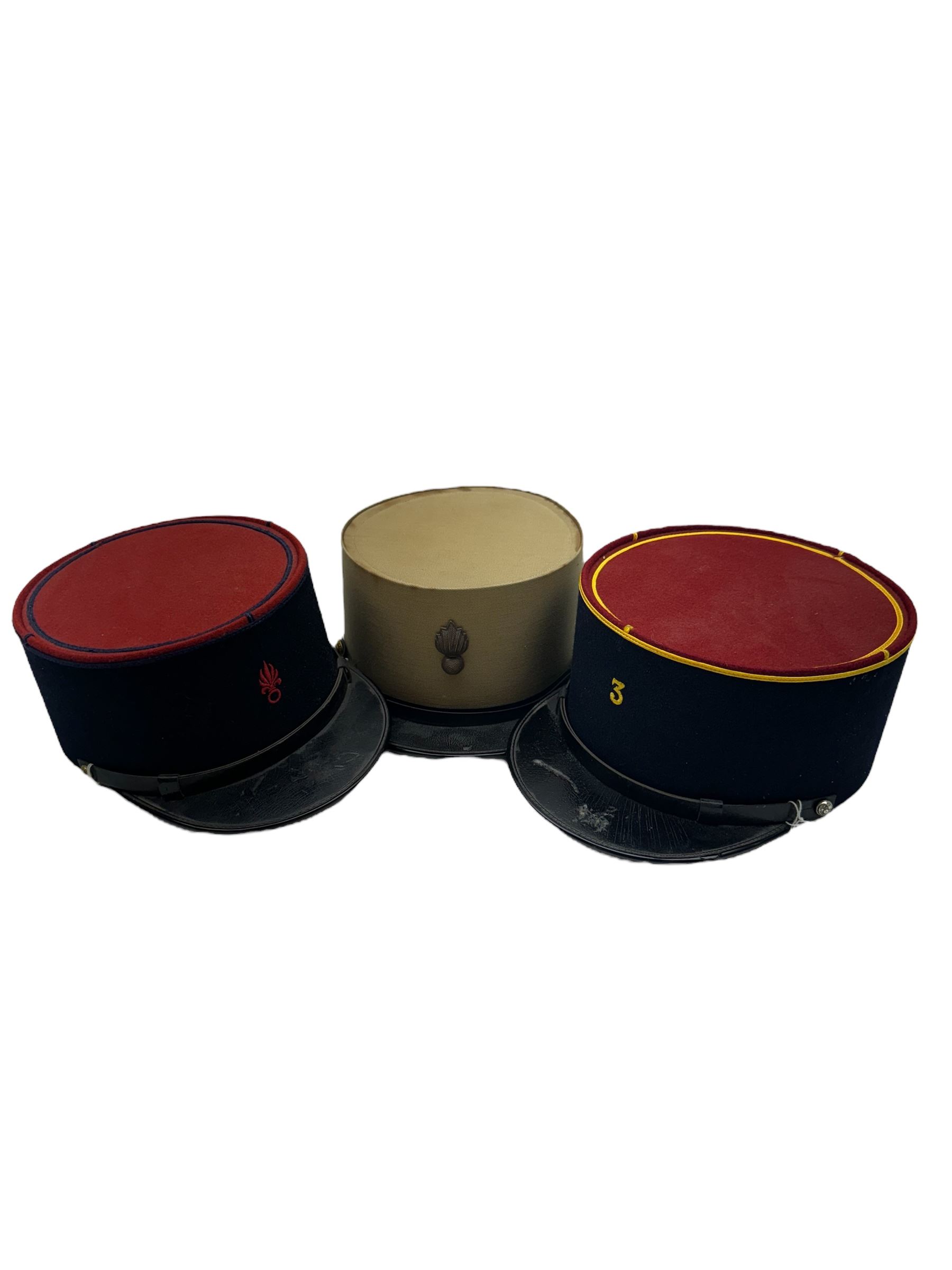 Three French Foreign Legion Kepis; two infantry examples and the third Calvary, each with black peak, original leather sweatband and markers mark stamped inside 