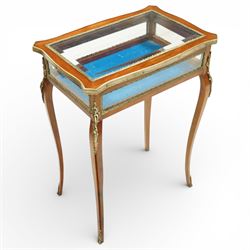 Early 20th century French mahogany bijouterie table, the hinged shaped rectangular top with brass edge and gilt-metal foliate slip enclosing bevelled glass plate, raised on cabriole supports with applied gilt-metal cartouche and foliate mounts