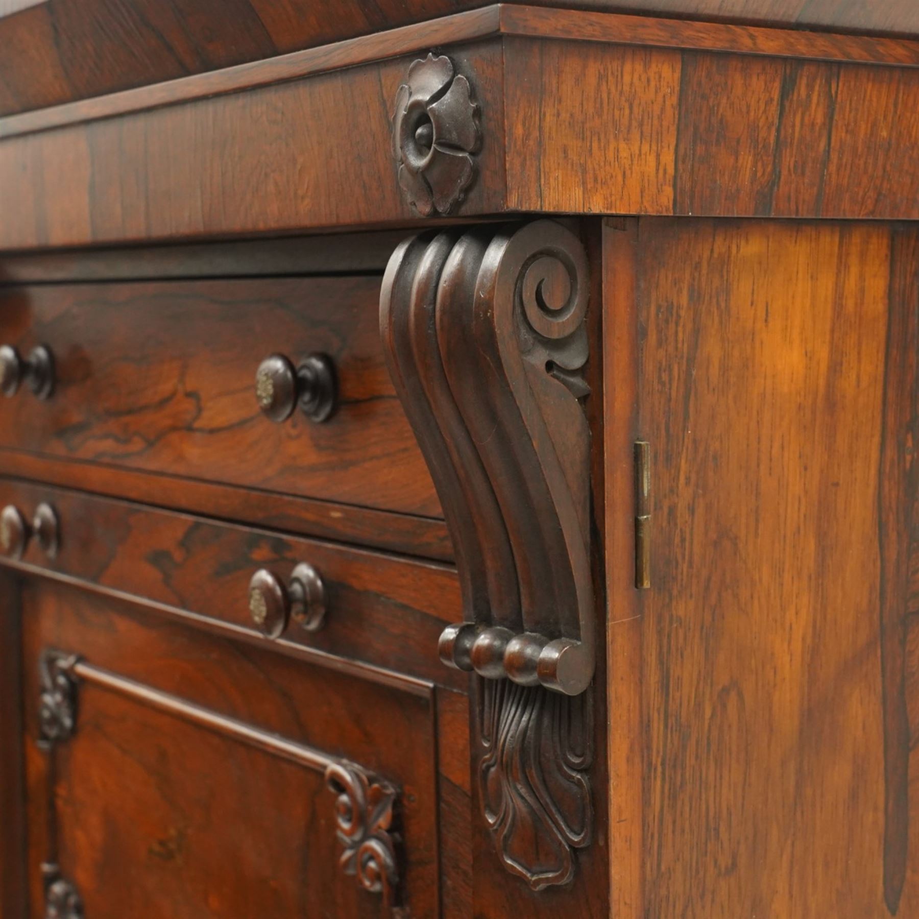 Victorian rosewood Wellington secretaire chest, the projecting stepped cornice over a banded frieze with moulded rosette mounts, single drawer over a secretaire fall-front opening to reveal a maple lined interior with assorted pigeonholes and correspondence drawers, over a lappet carved lower edge with four graduating drawers below, each with turned pull handles, flanked by hinged lock to the right and plain stile to the left surmounted by reeded corbels, raised on a skirted base