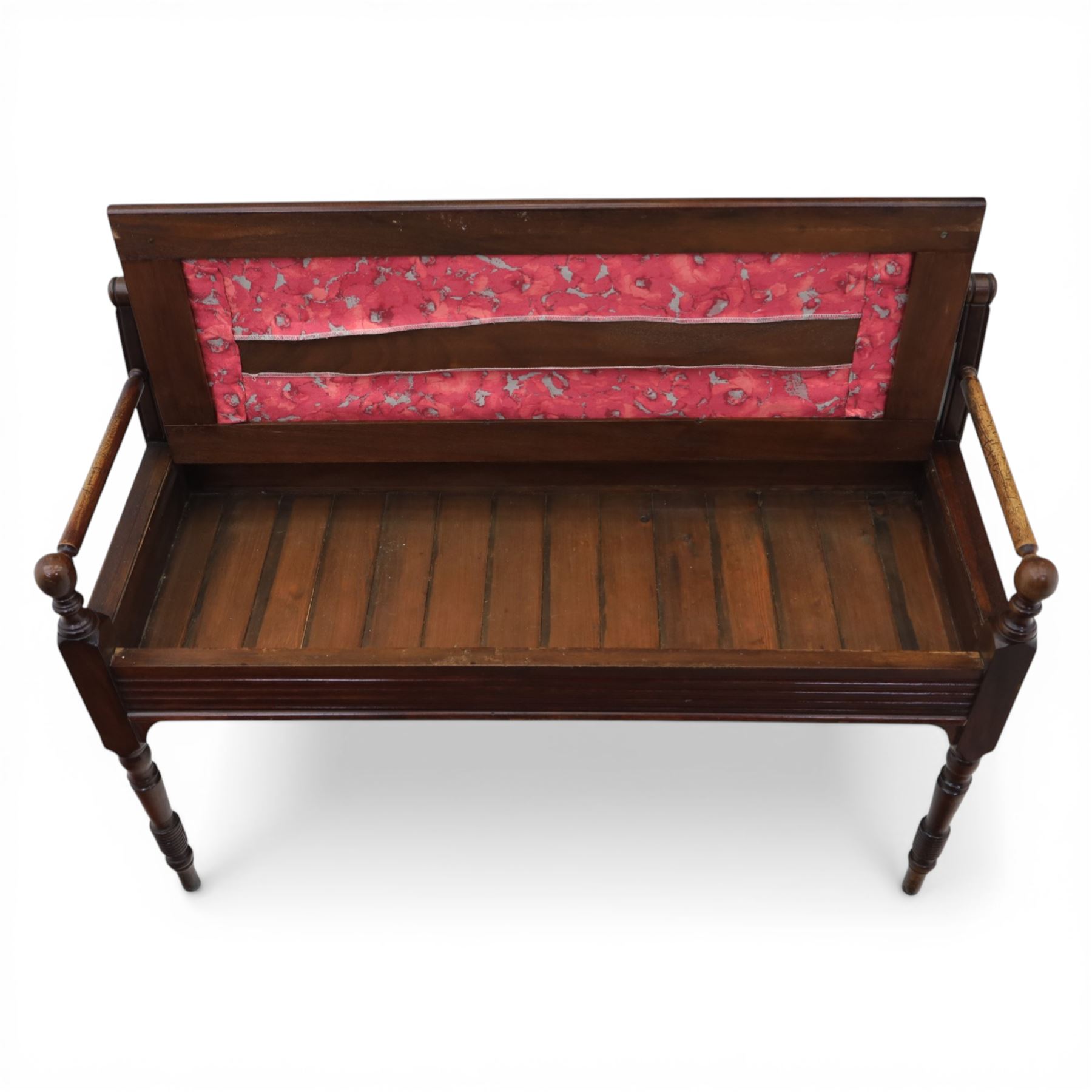 Early 20th century mahogany hall bench, spindle turned back with shaped top rail and open arms terminating in ball finials, upholstered seat within a fluted frieze, raised on turned tapering supports