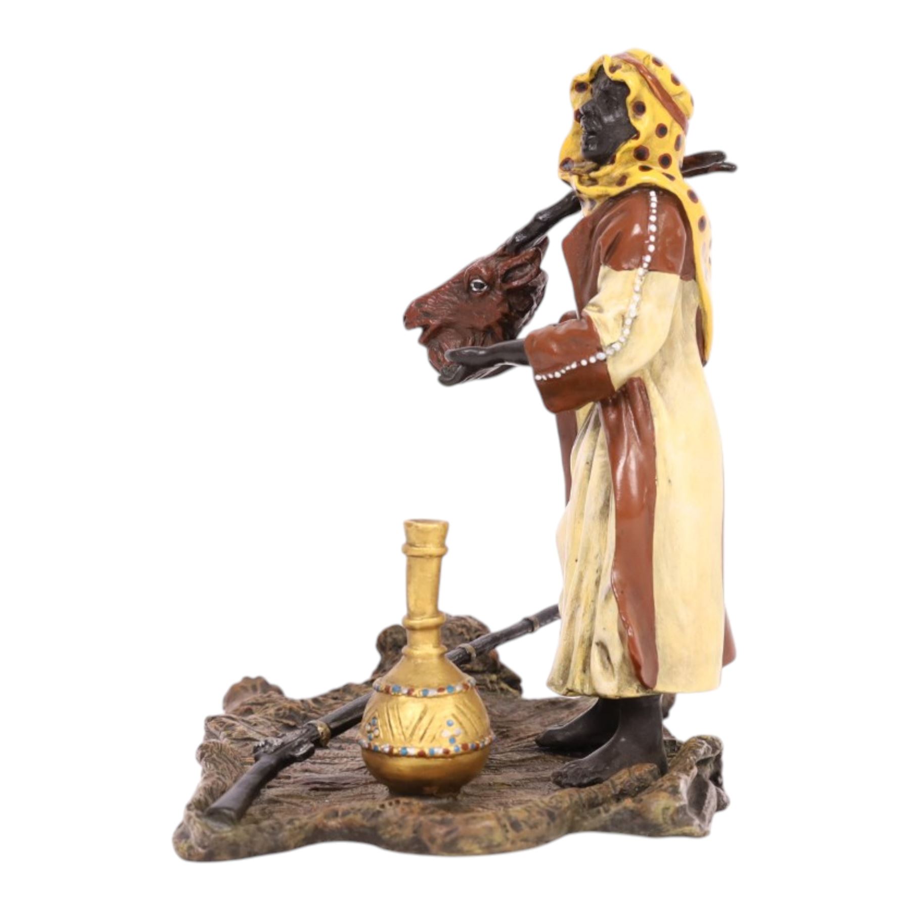 After Bergman - bronze Arab trader holding an antelope head while standing on a tiger skin, with a rifle and jars at his feet, H14cm