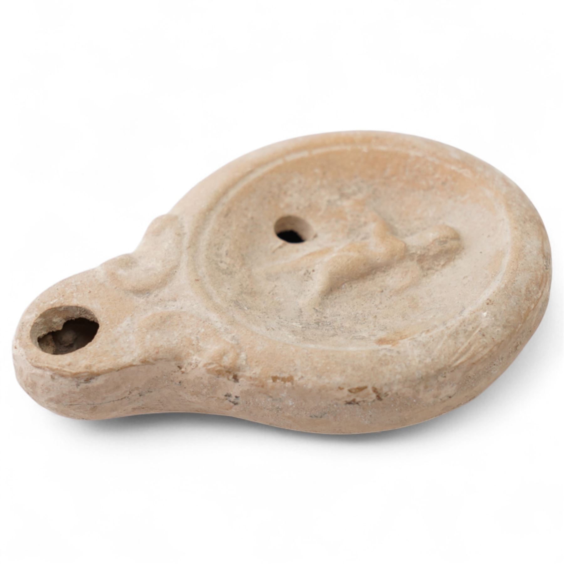 Roman terracotta oil lamp with Cupid motif c.1st-2nd Century AD, mould-made, with a rounded body and volute nozzle, the concave discus decorated in relief with a figure of Cupid in motion, depicted with wings and bow, within a raised circular border, with central fill-hole and wick-hole at the nozzle W 8.5cm
Provenance: By the vendor’s repute, acquired/collected in the Middle East (Dead Sea area/Syria) in the 1960s
