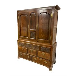 18th century oak housekeepers cupboard, two panelled doors above floral carved panels, three short and two long drawers, raised on ogee bracket feet