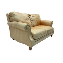 Two seat sofa, upholstered in pale tan leather with scrolled arms