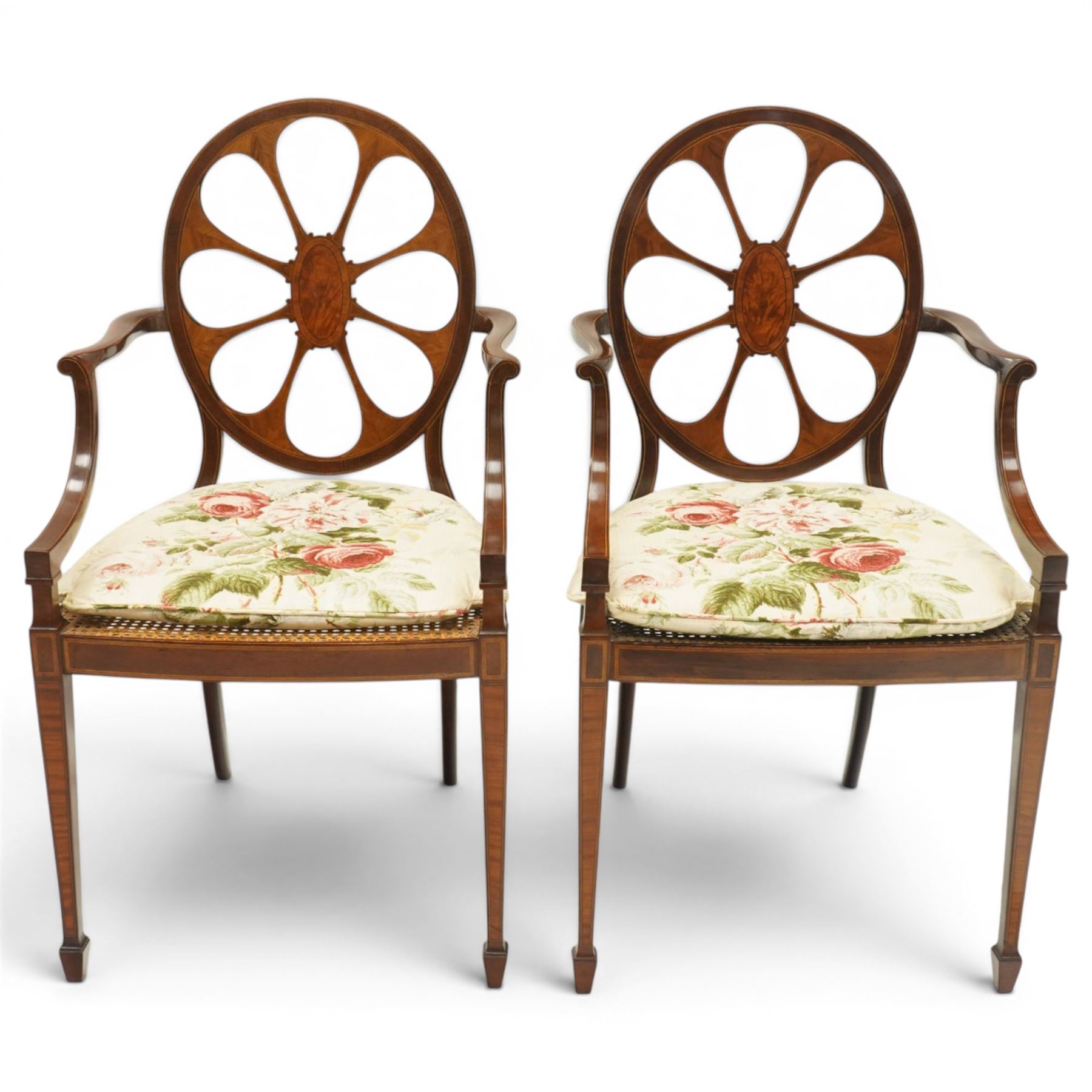 Hampton & Sons (Pall Mall 1830-1957) - Pair of Edwardian inlaid mahogany wheel-back elbow chairs, the pierced oval backs with chequered stringing and cross banding, out-swept arms over canework seats, banded seat rail over square tapering supports with spade feet, stamped to underside
Provenance: Kirkham Hall