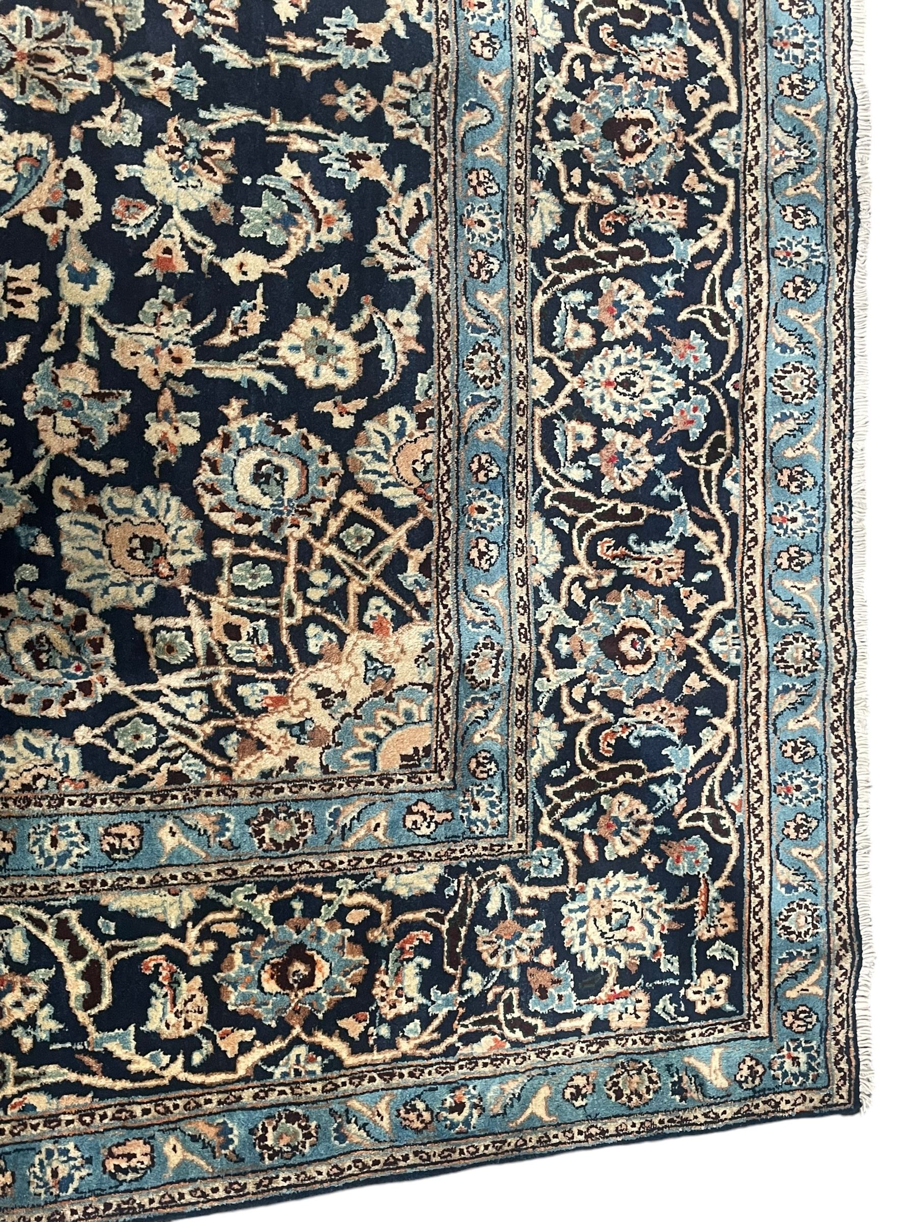 Persian Kashan indigo ground rug, the rosette medallion decorated with projecting palmettes, on a field of swirling leafy branches and decorated with further palmettes, the scrolling border with repeating stylised plant motifs, within floral pattern guard stripes